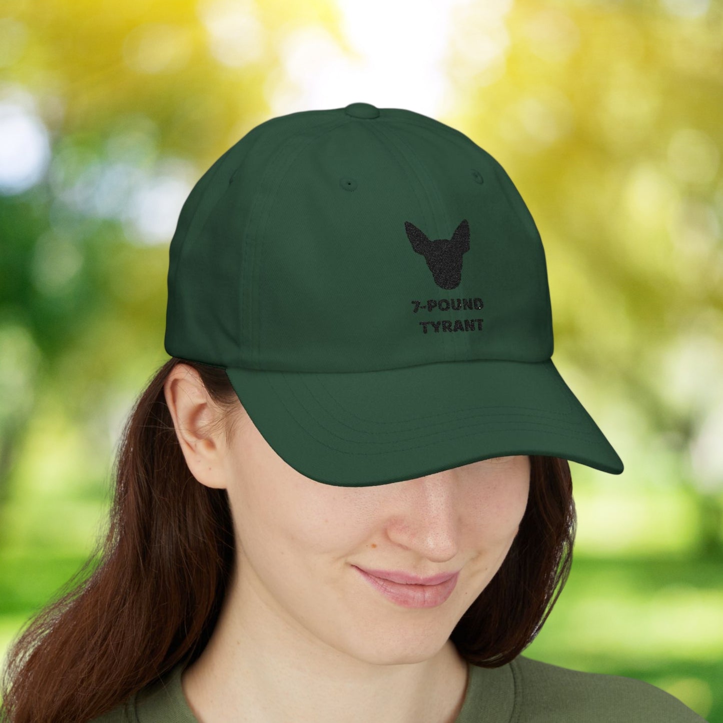 Spruce "7-Pound Tyrant" Miniature Pinscher cap with black dog silhouette embroidery, worn by a woman.