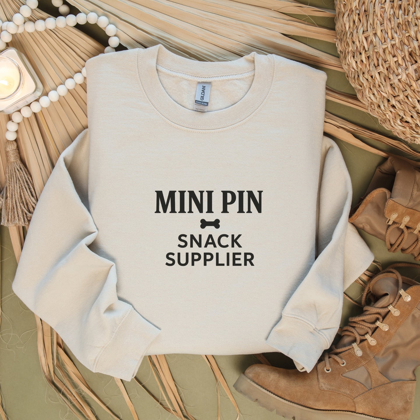 Flat lay of a sand "Mini Pin Snack Supplier" Miniature Pinscher unisex sweatshirt.