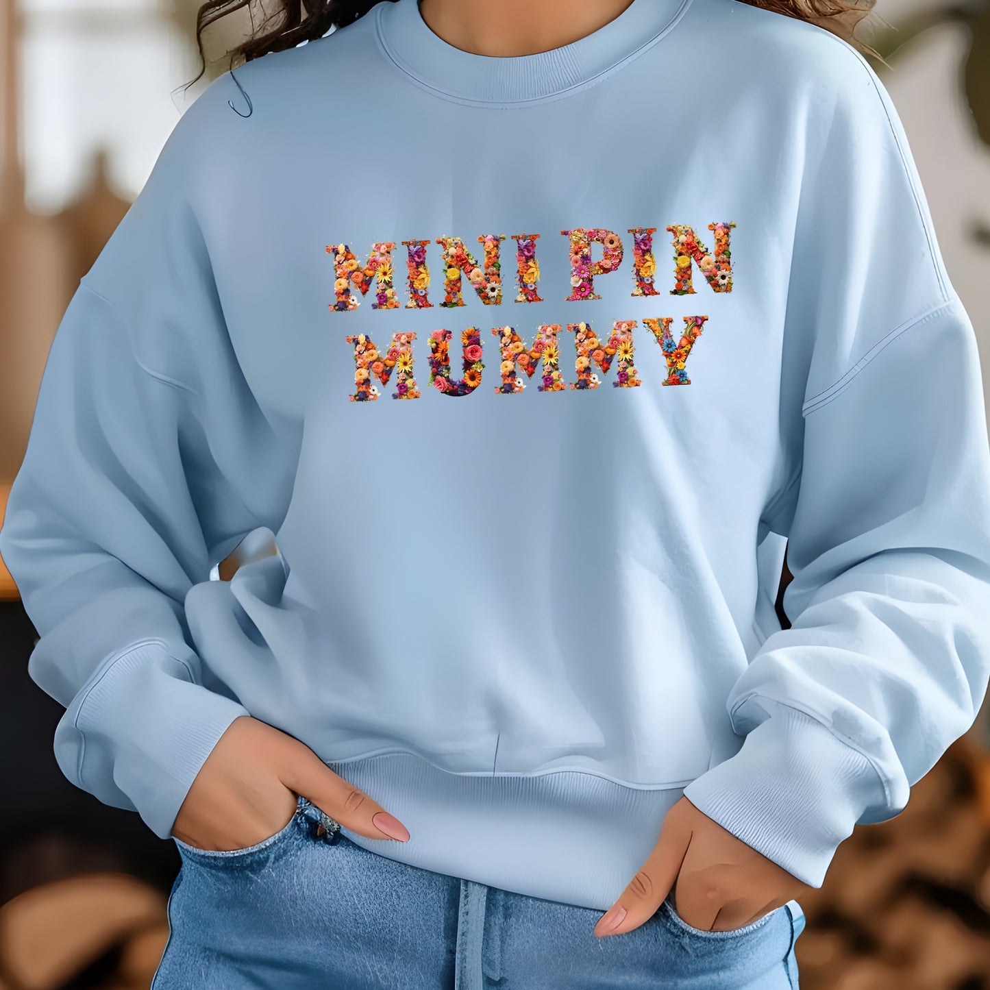 Woman wearing a light blue floral"MINI PIN MUMMY" Miniature Pinscher women’s sweatshirt, stylish street look.