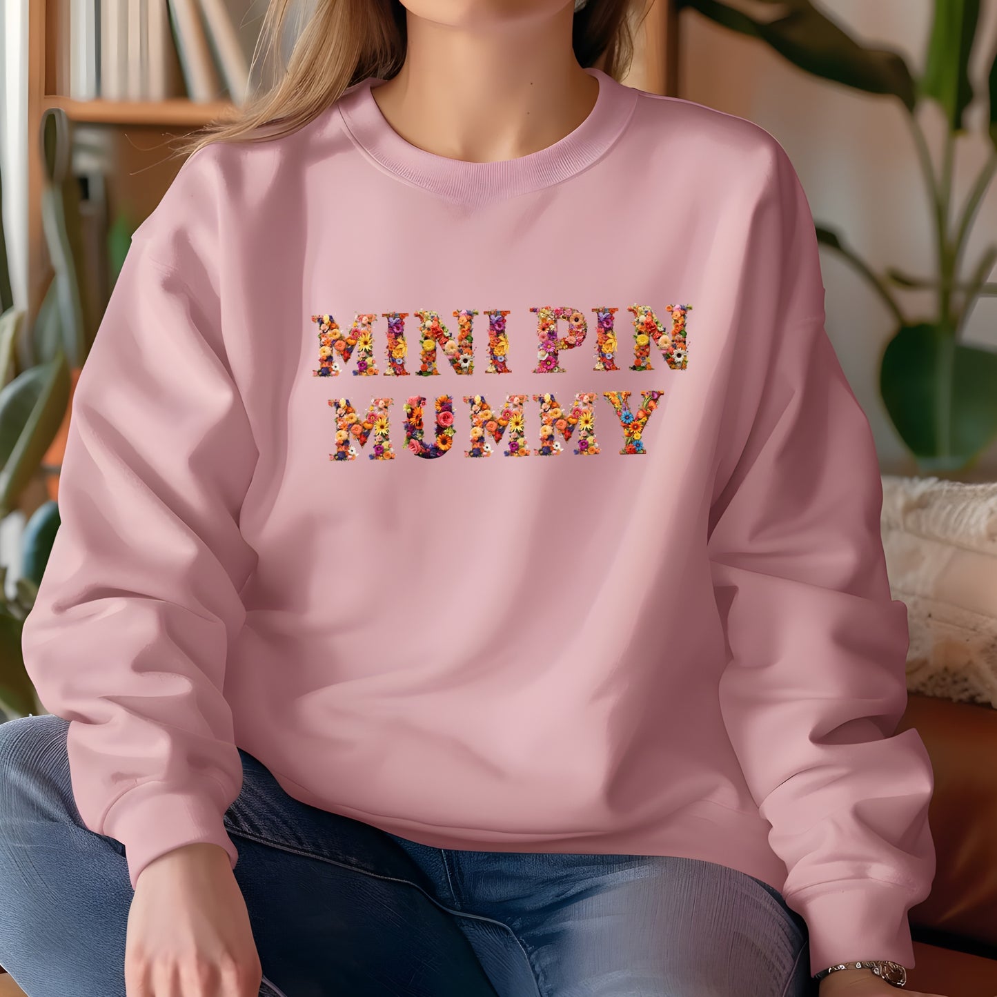 Woman wearing a light pink floral "MINI PIN MUMMY" Miniature Pinscher women’s sweatshirt, stylish street look
