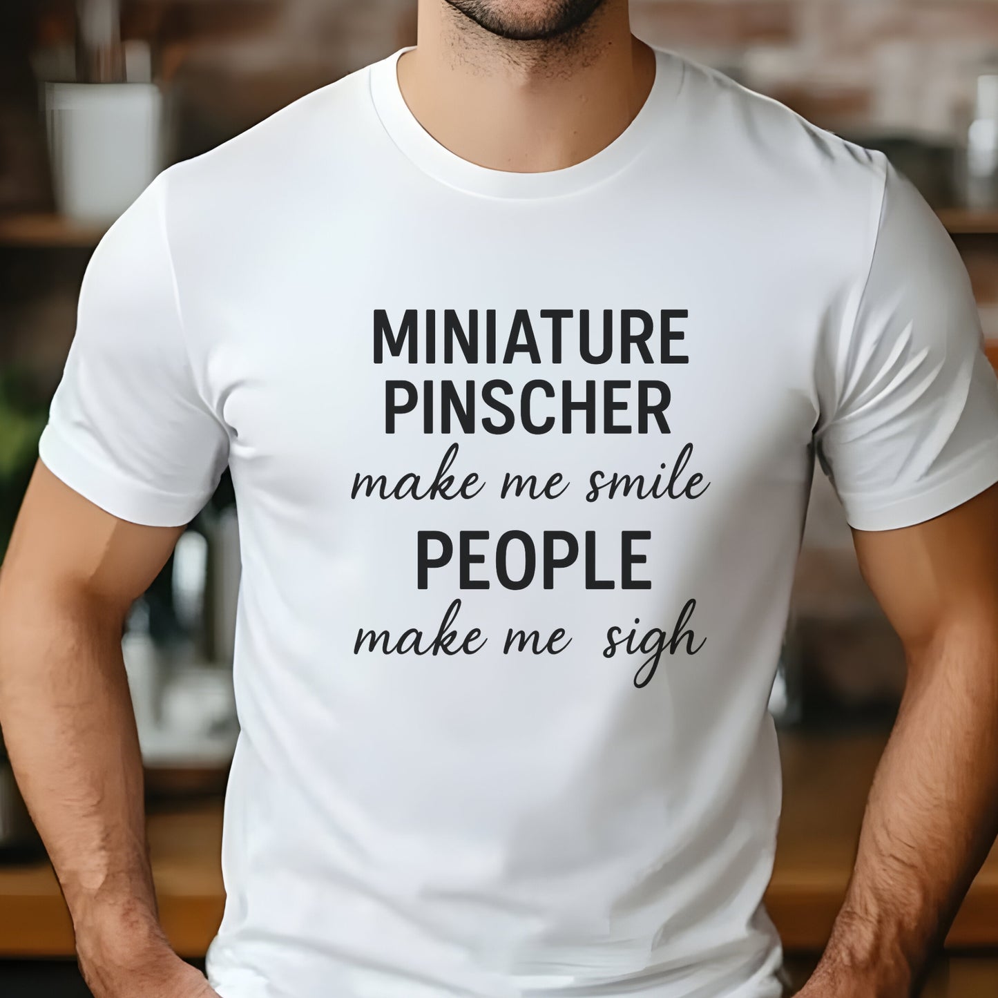 Man wearing a white "Miniature Pinscher make me smile, people make me sigh" unisex t-shirt, casual kitchen background