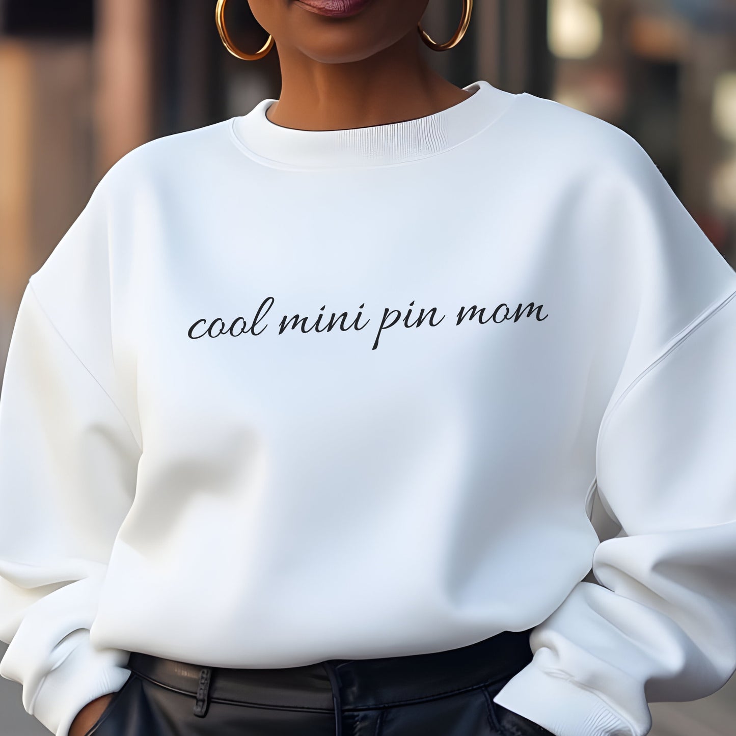 Woman wearing a white "cool mini pin mom" Miniature Pinscher women’s sweatshirt, hands in pockets, casual style