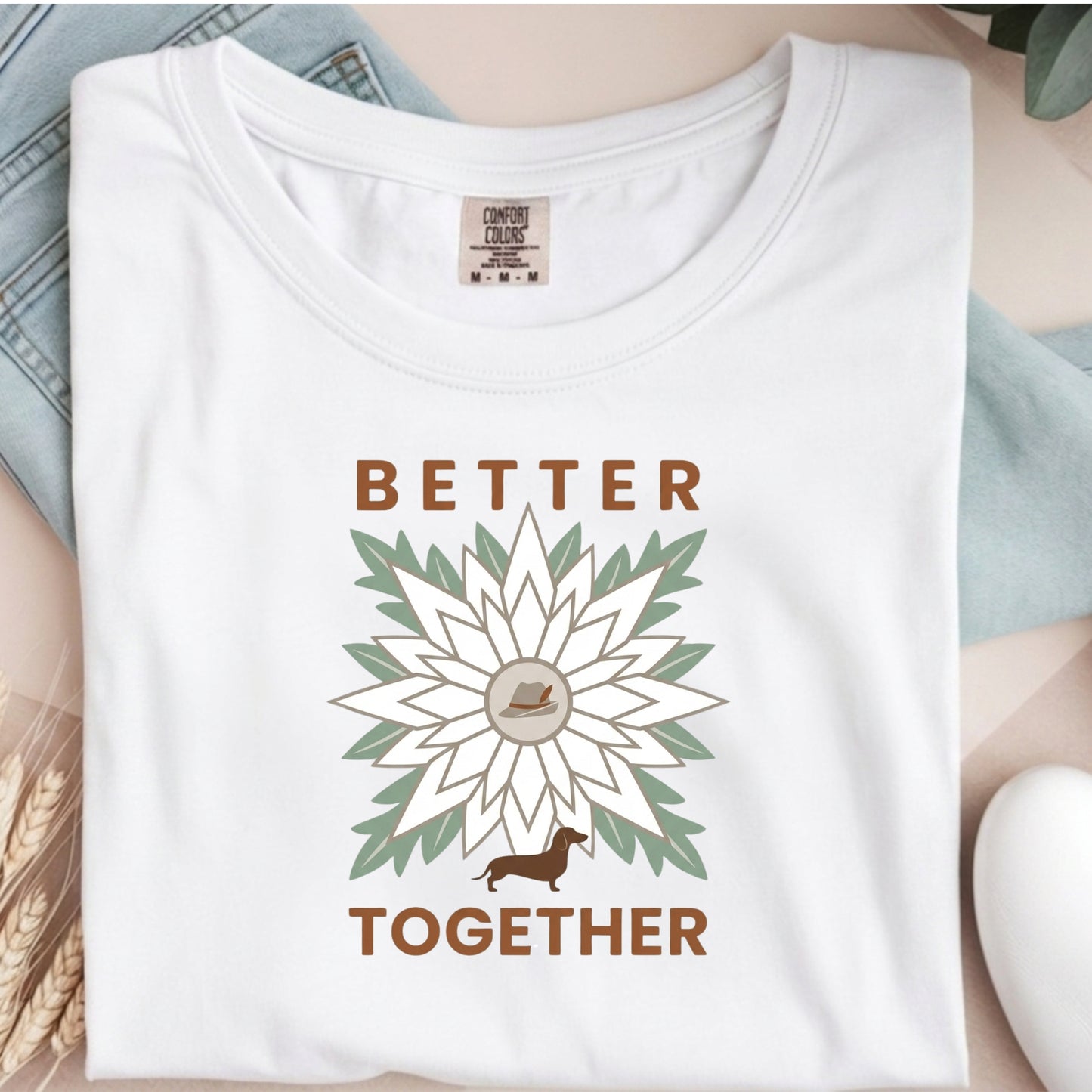 White t-shirt with 'Better Together' design featuring a sunflower and dachshund, displayed on a surface.