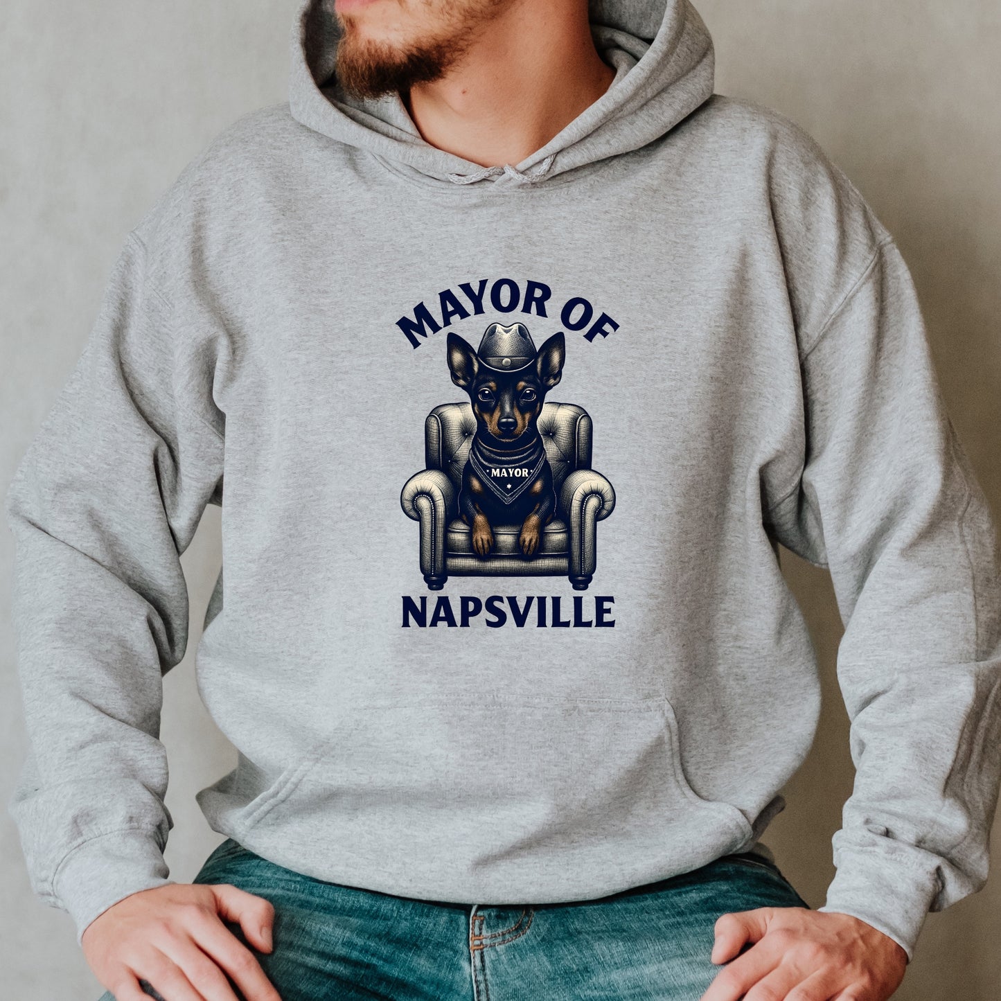 Man wearing a grey "Mayor of Napsville" Miniature Pinscher hoodie with a dog on an armchair and funny nap design