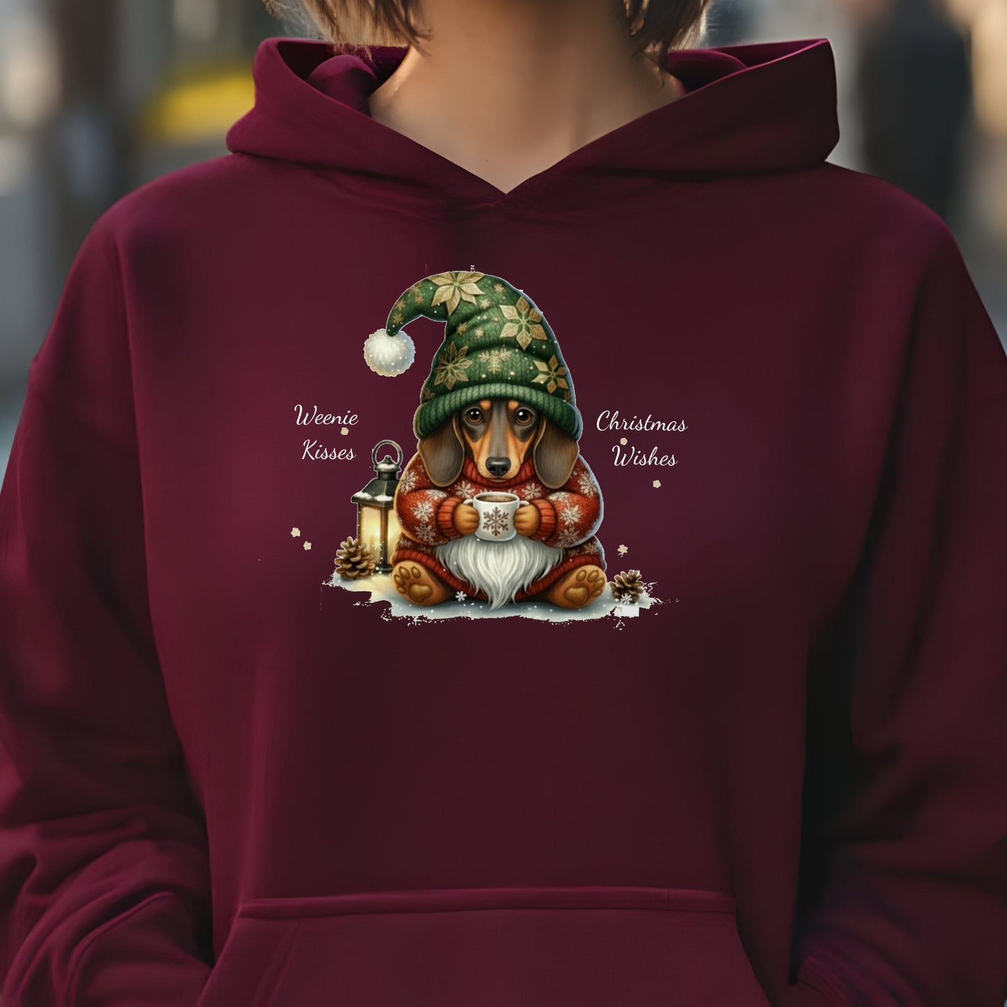 Maroon hoodie with a Christmas-themed design of a dachshund wearing a green hat and holding a lantern.