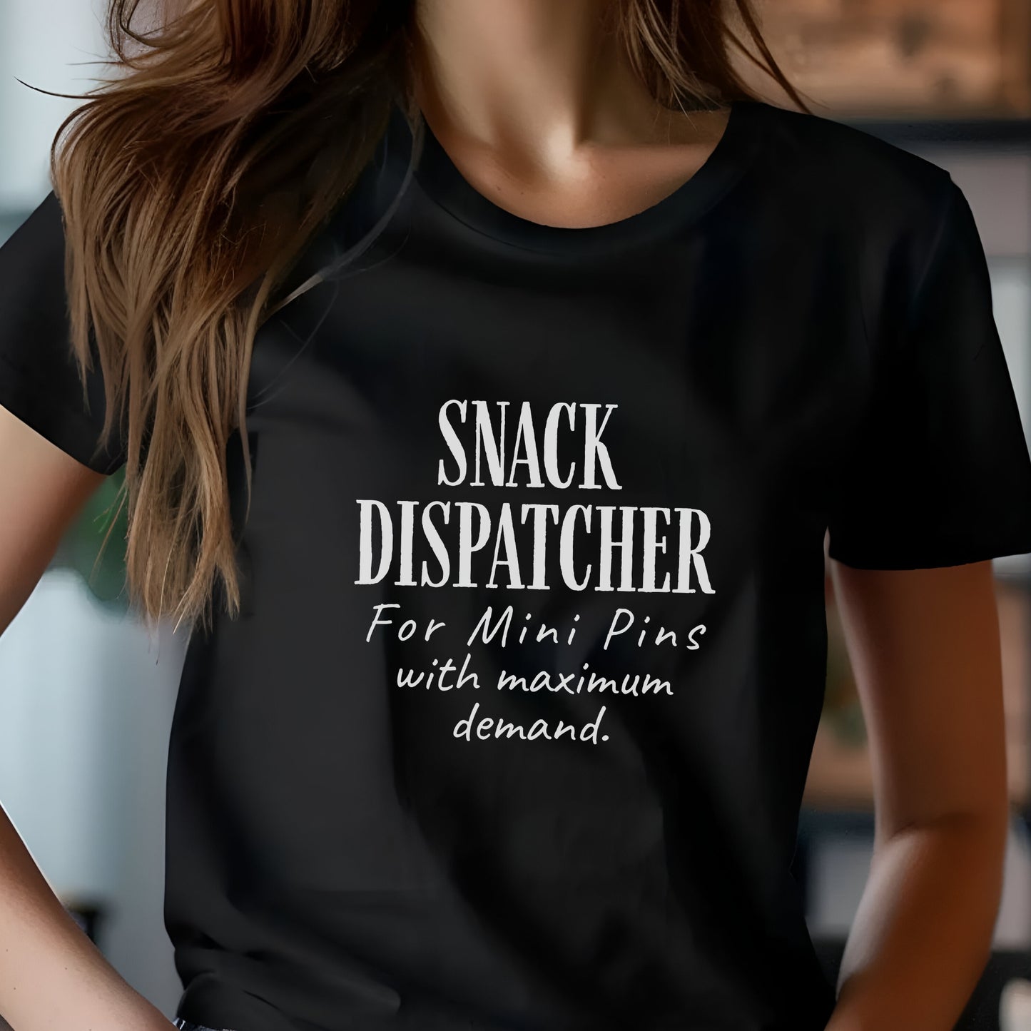 Woman wearing a black t-shirt with black text: "SNACK DISPATCHER – For Mini Pins with maximum demand