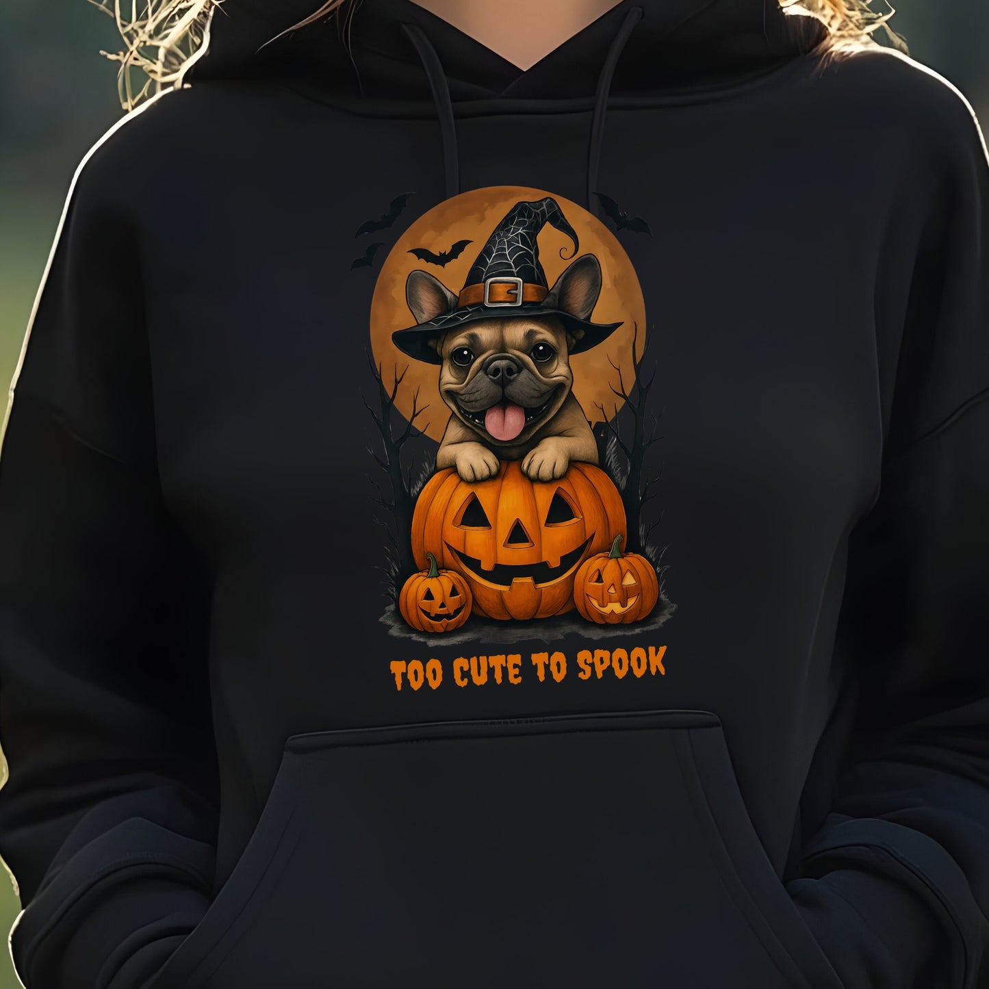 French Bulldog wearing a witch hat with pumpkins and bats, Halloween theme on a black hoodie.