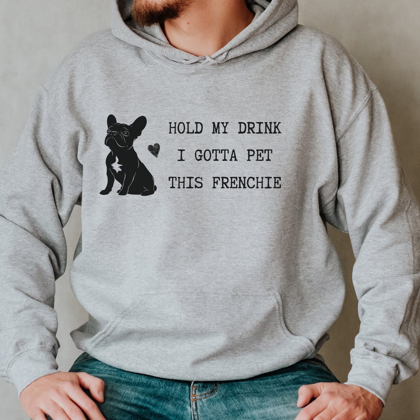 Sport grey hoodie with a black line-art French Bulldog illustration and the bold text “Hold my drink, I gotta pet this Frenchie” printed on the front.