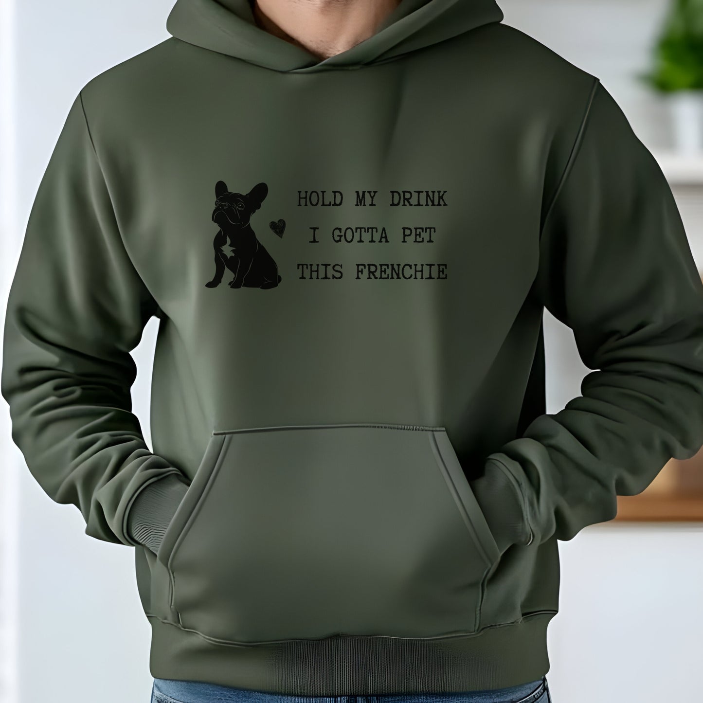 Military green hoodie with a black line-art French Bulldog illustration and the bold text “Hold my drink, I gotta pet this Frenchie” printed on the front.