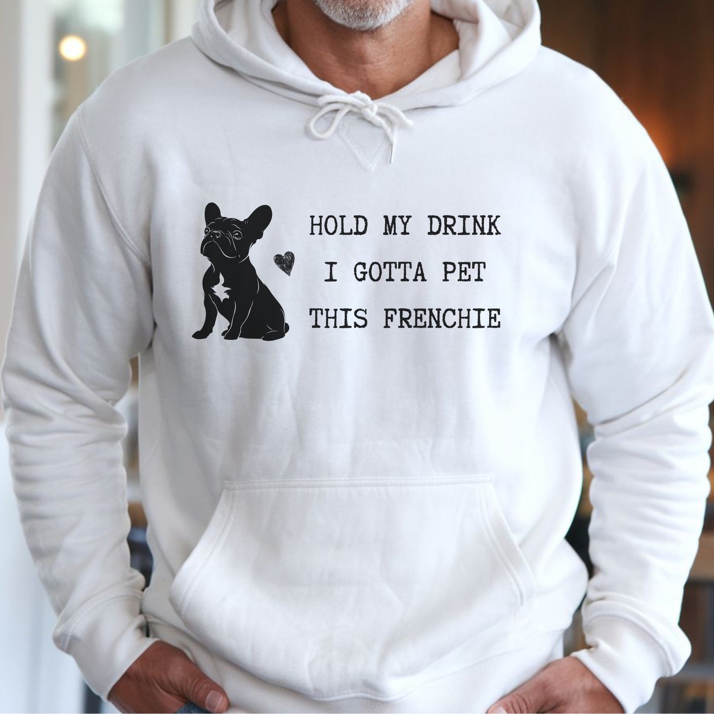 White hoodie with a black line-art French Bulldog illustration and the bold text “Hold my drink, I gotta pet this Frenchie” printed on the front.
