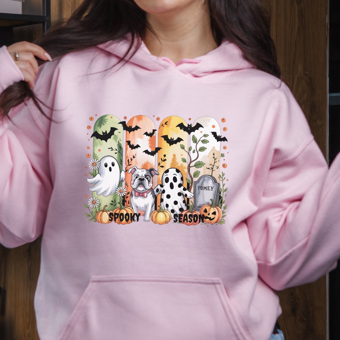 Light pink hoodie with Halloween-themed print of small dogs in ghost costumes, bats, pumpkins, and “Spooky Season” text on the front.
