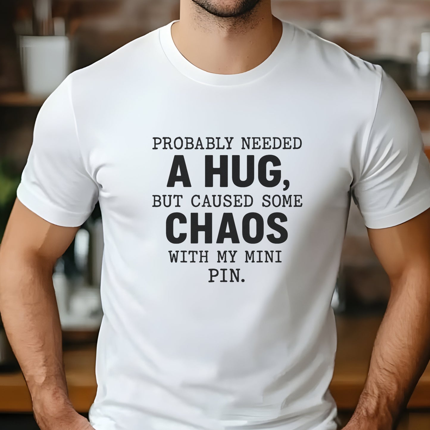 White unisex t-shirt with white text: "Probably needed a hug, but caused some chaos with my Mini Pin." centered on the chest