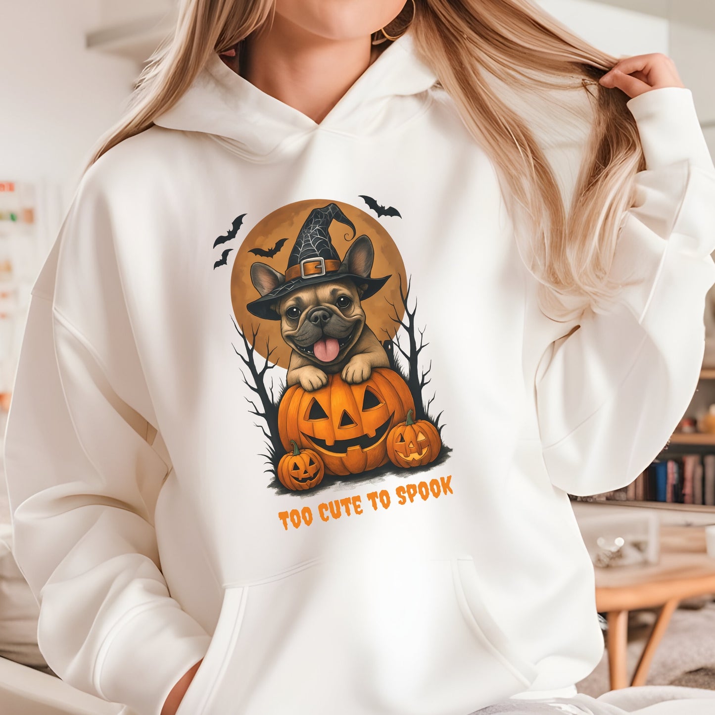 French Bulldog wearing a witch hat with pumpkins and bats, Halloween theme on a sand hoodie.