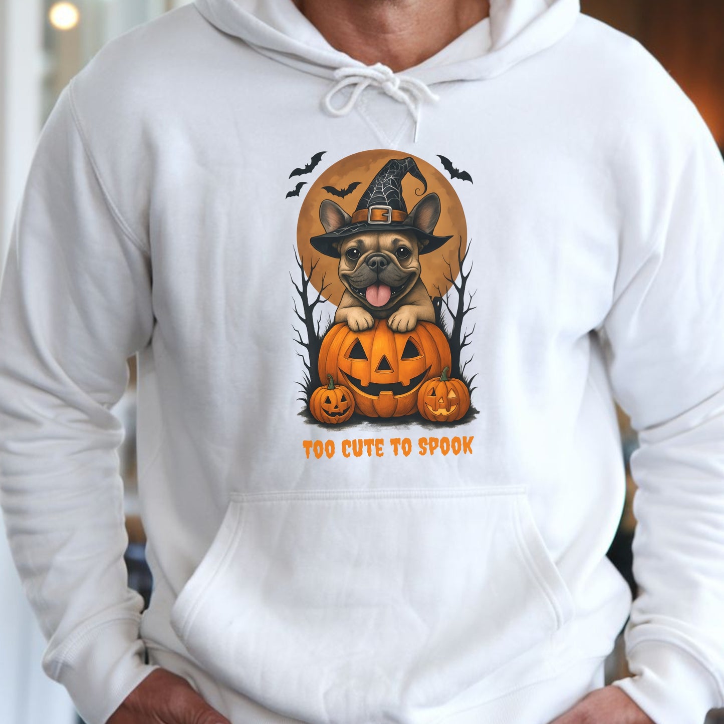 French Bulldog wearing a witch hat with pumpkins and bats, Halloween theme on a white hoodie.