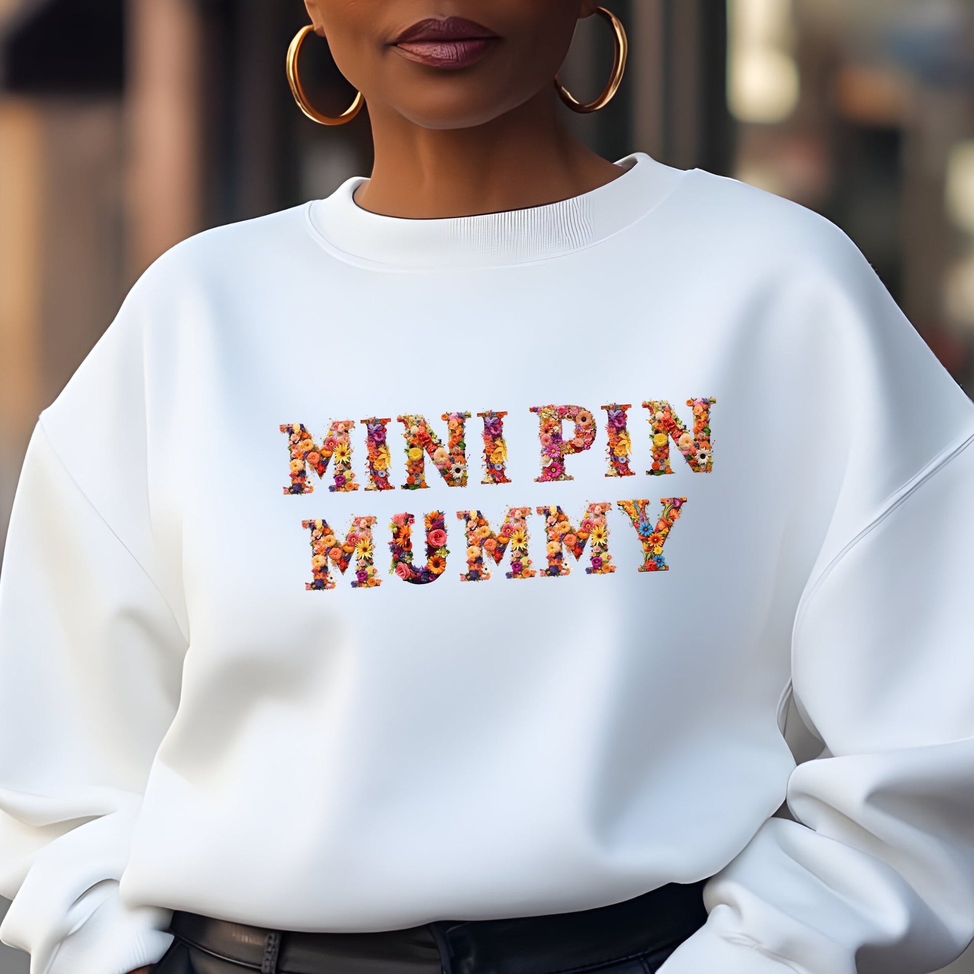 Woman wearing a white floral "MINI PIN MUMMY" Miniature Pinscher women’s sweatshirt, stylish street look