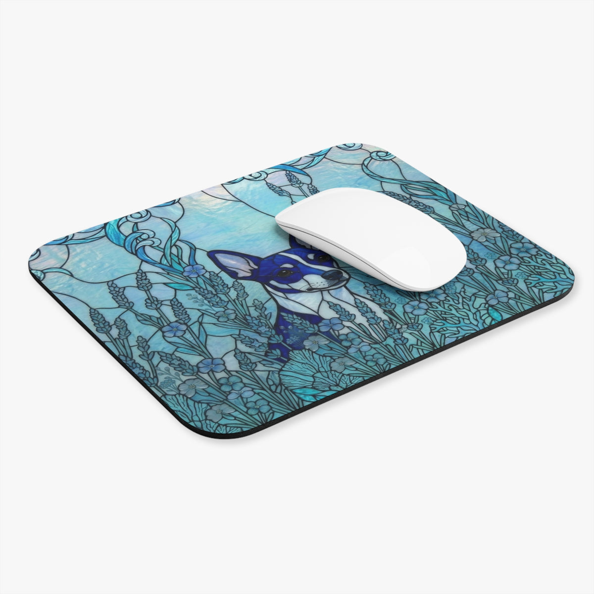 A rectangular computer mouse pad with rounded corners, featuring a blue and teal stained-glass style illustration of a dog surrounded by flowers. A white wireless mouse is placed on top of the pad, which is photographed on a clean white background.