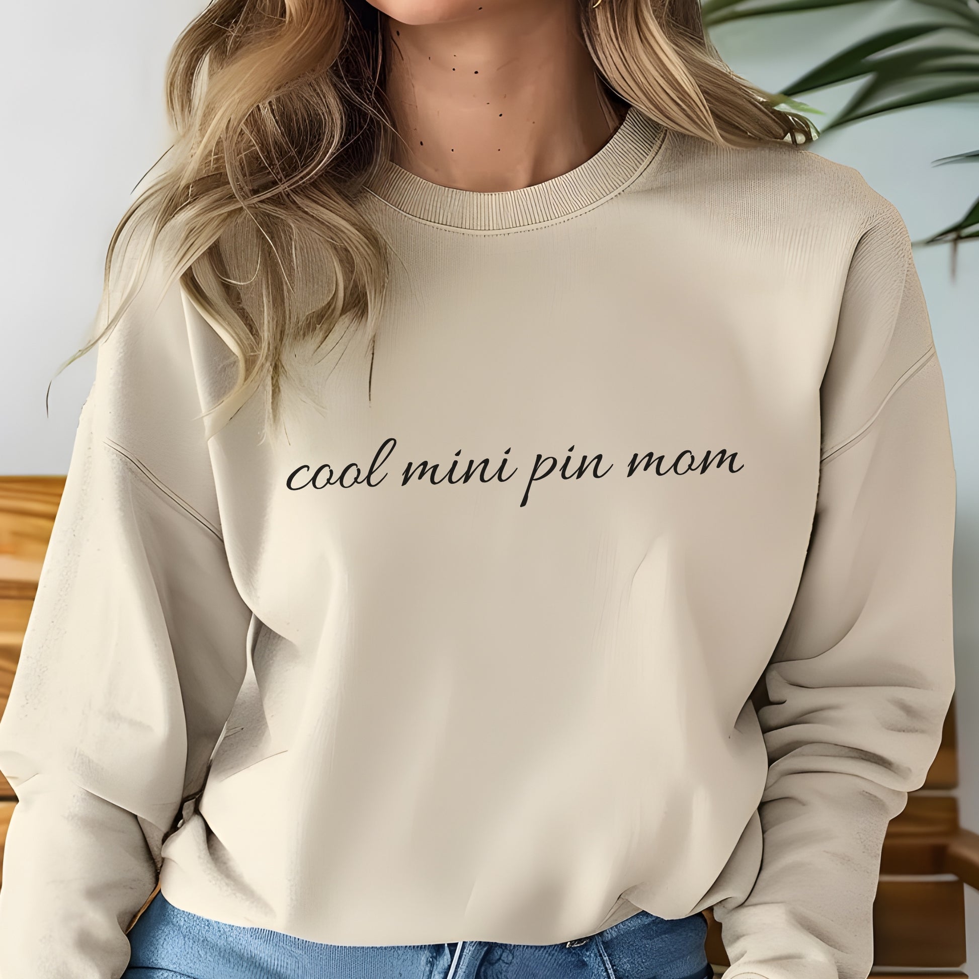 Woman wearing asand "cool mini pin mom" Miniature Pinscher women’s sweatshirt, hands in pockets, casual style