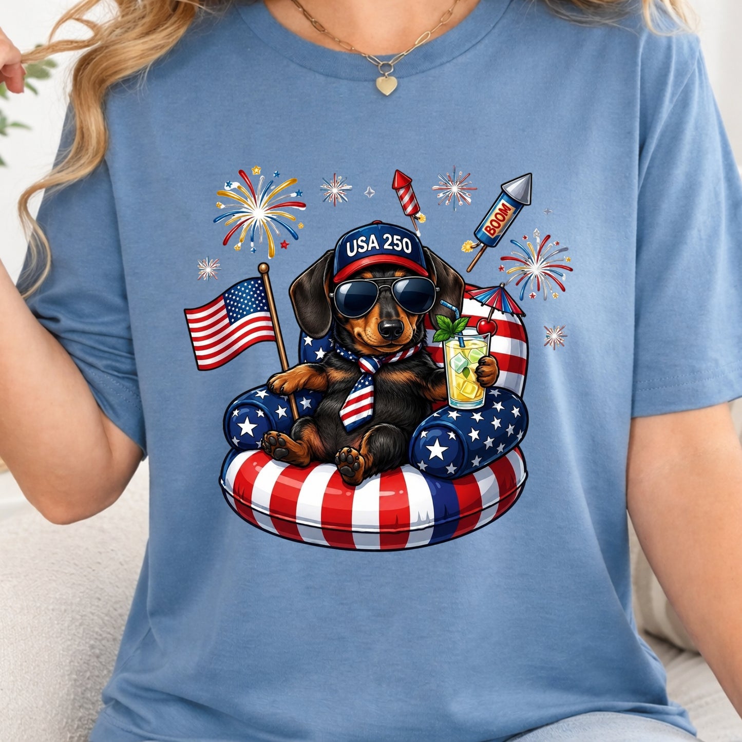 Person wearing a blue t-shirt with a 4th of July-themed graphic featuring a dog in an American flag float.