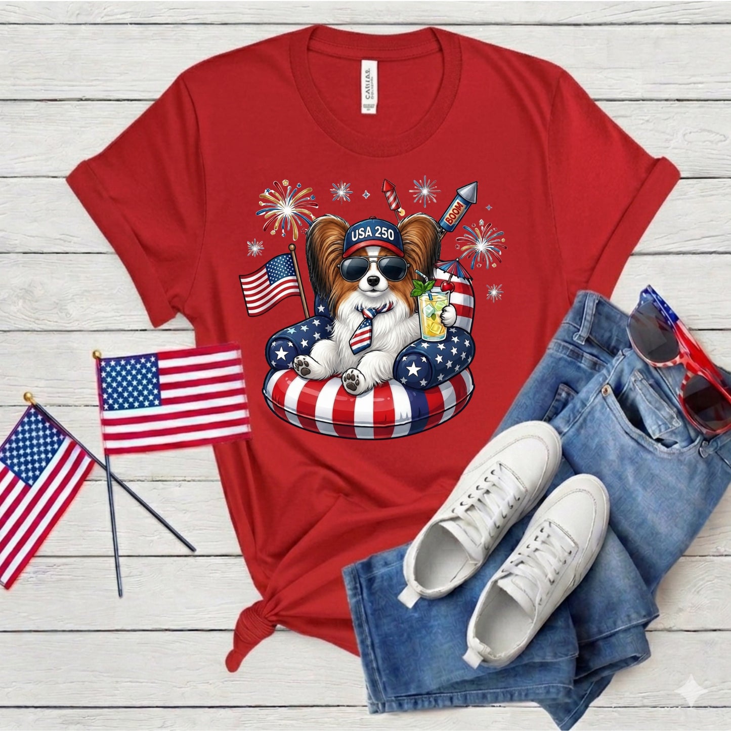 Red t-shirt with a dog graphic, American flags, and sunglasses on a wooden surface.