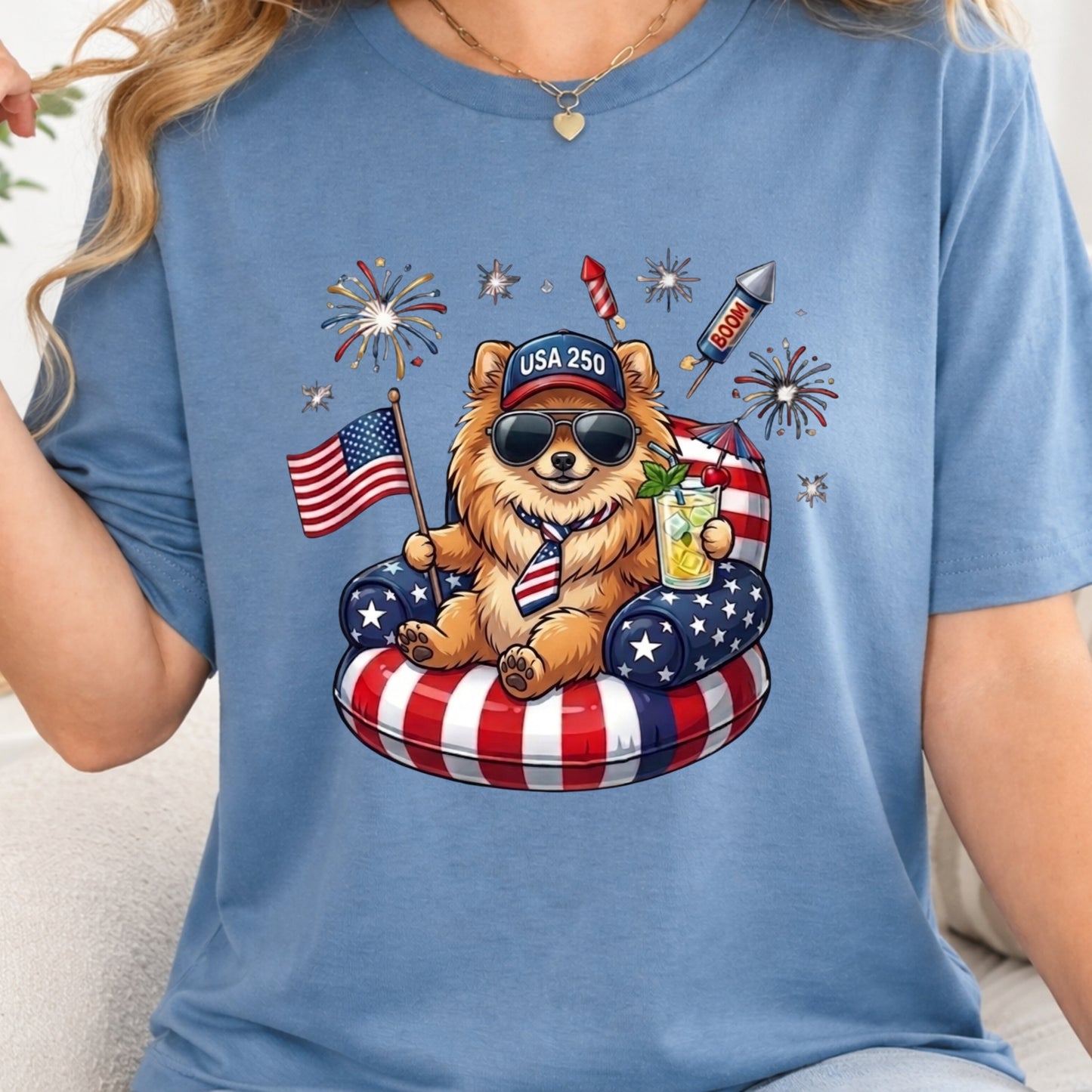 Blue t-shirt with a bear graphic holding an American flag and a drink, surrounded by fireworks and stars.