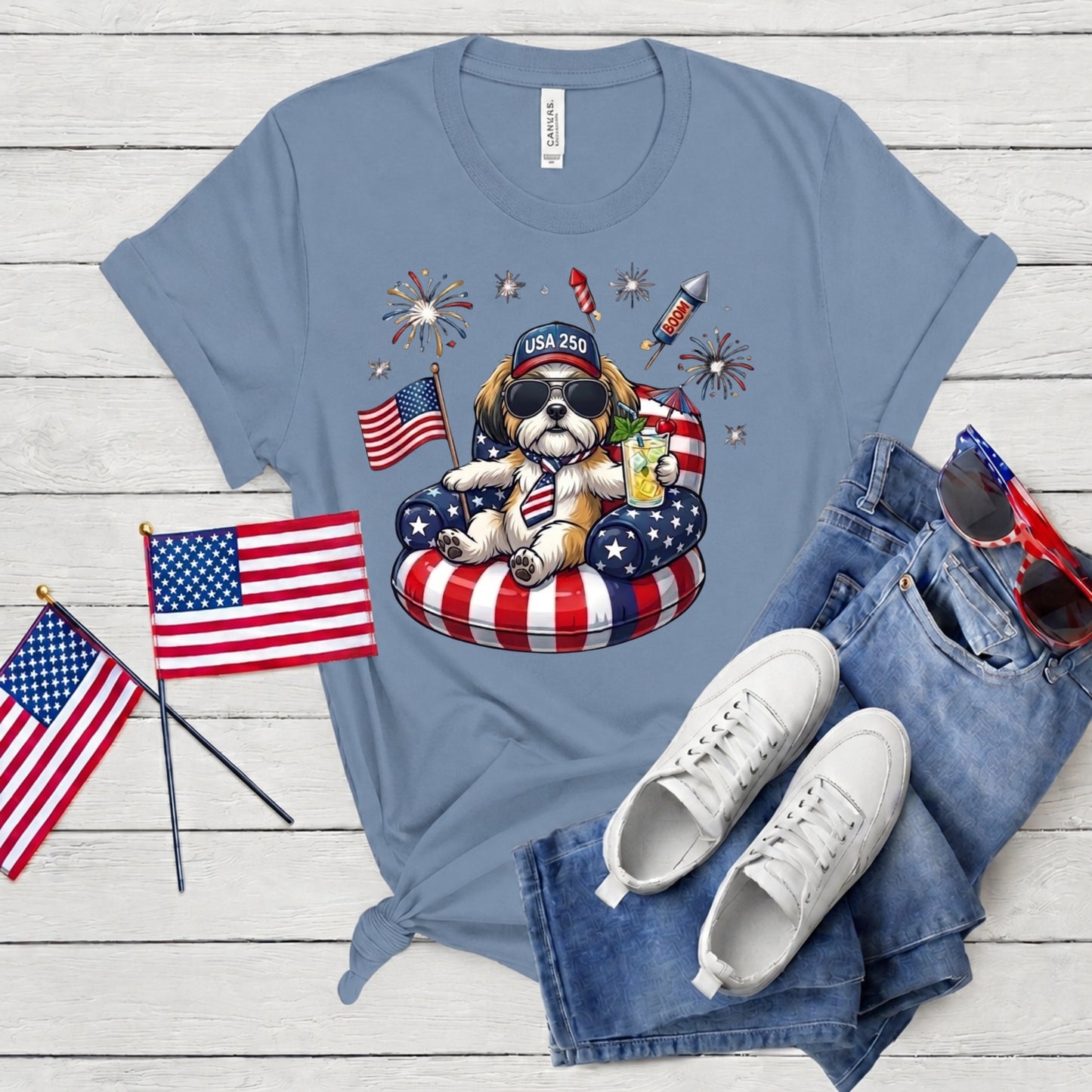 Blue t-shirt with a bear graphic, American flags, and sunglasses on a wooden surface.