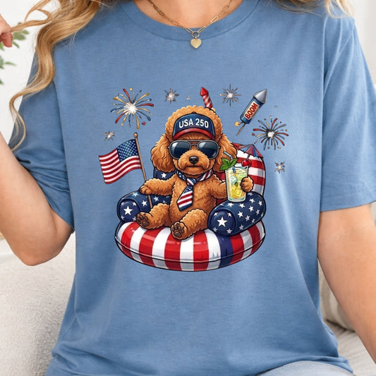 Blue t-shirt with a bear graphic holding an American flag and a drink, surrounded by fireworks and stars.