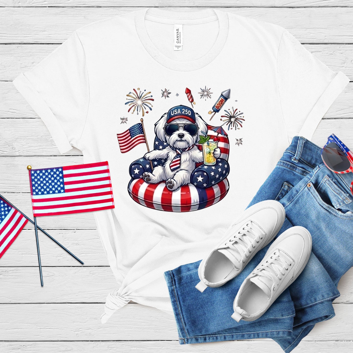 White t-shirt with a dog graphic, American flags, and jeans on a wooden surface