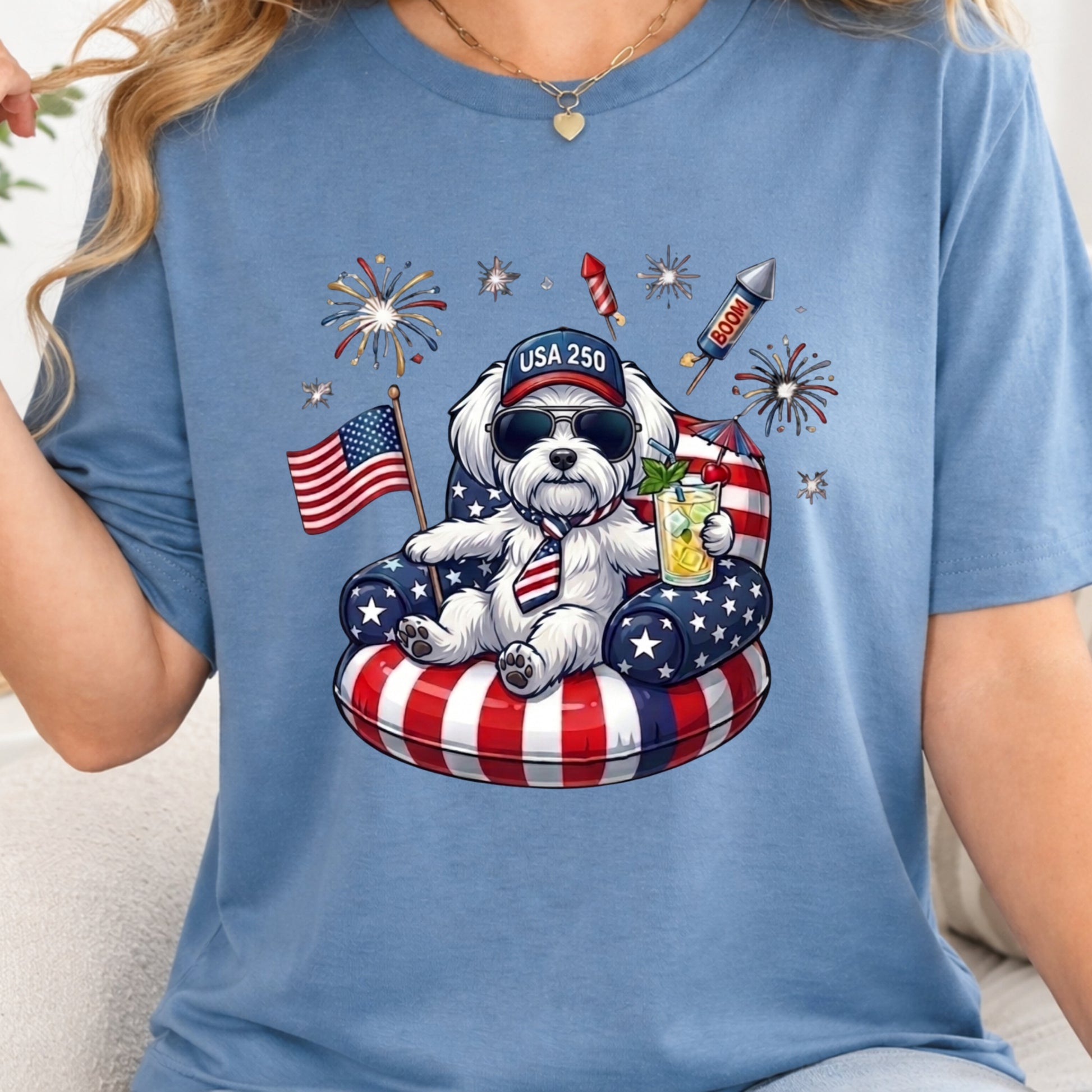Blue t-shirt with a bear graphic celebrating the 4th of July, featuring American flags and fireworks.
