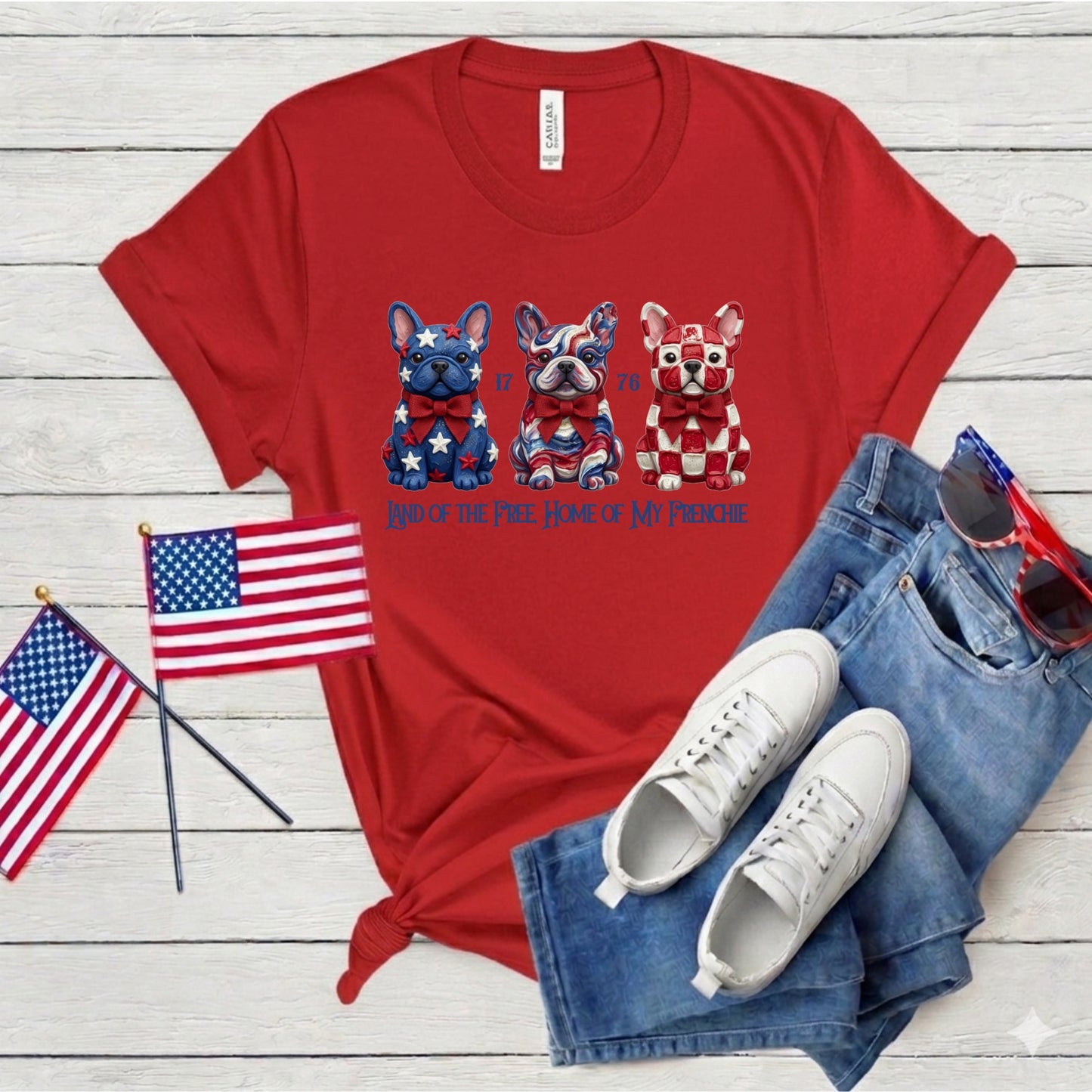 Red t-shirt with dog graphics and text, paired with jeans, sneakers, and American flags on a wooden surface.