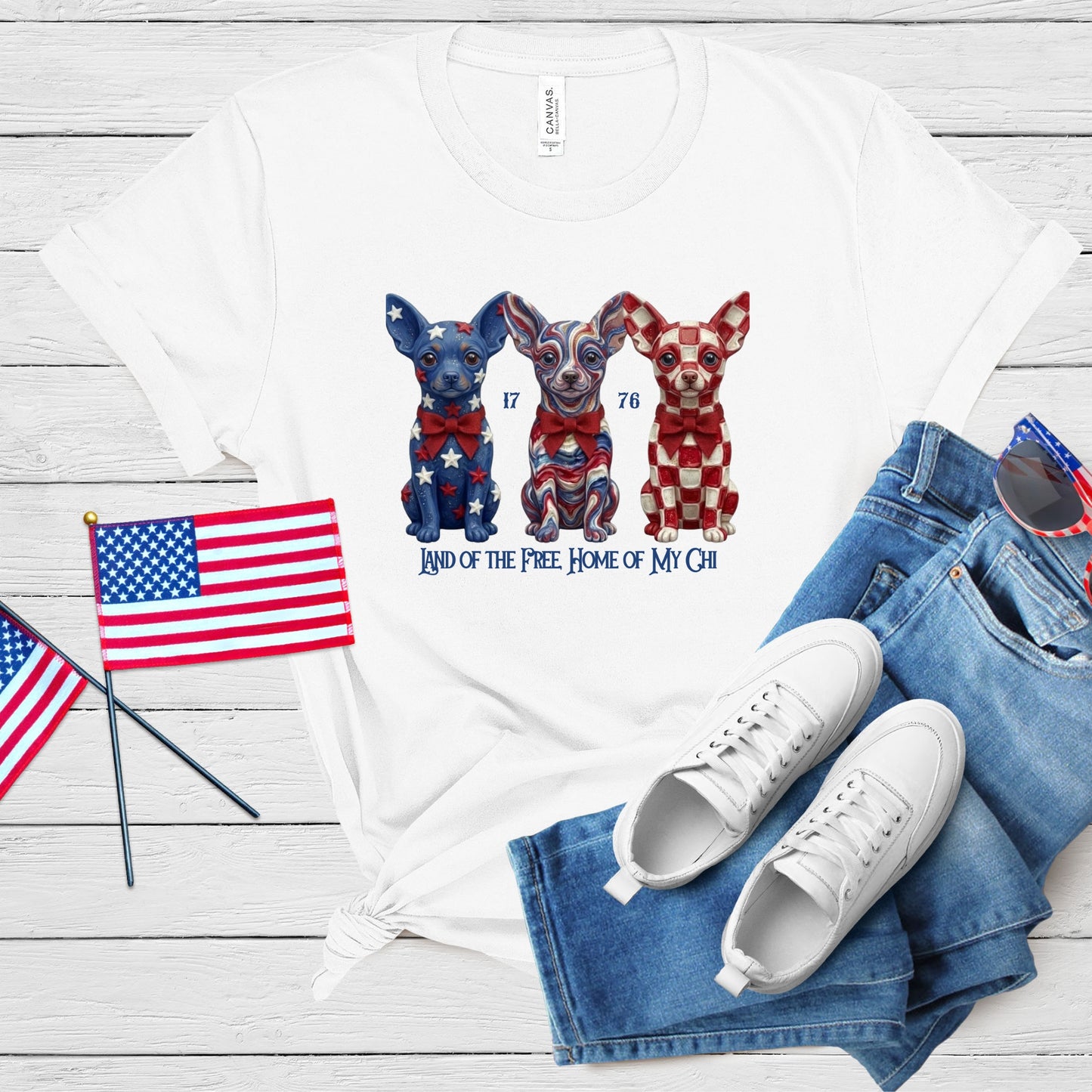White t-shirt with dog illustrations and text, paired with jeans and sneakers on a wooden surface.
