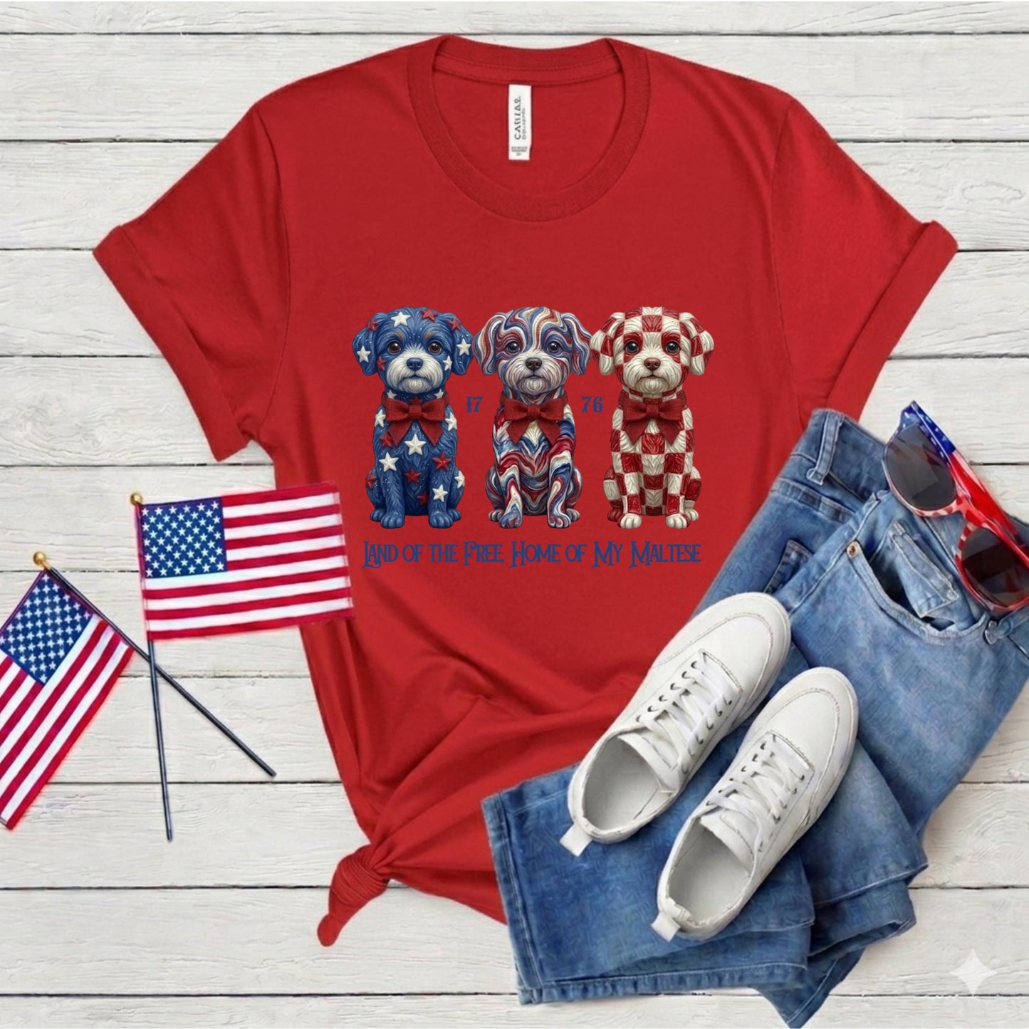 Red t-shirt with dog graphic, American flags, white sneakers, and blue jeans on a wooden surface