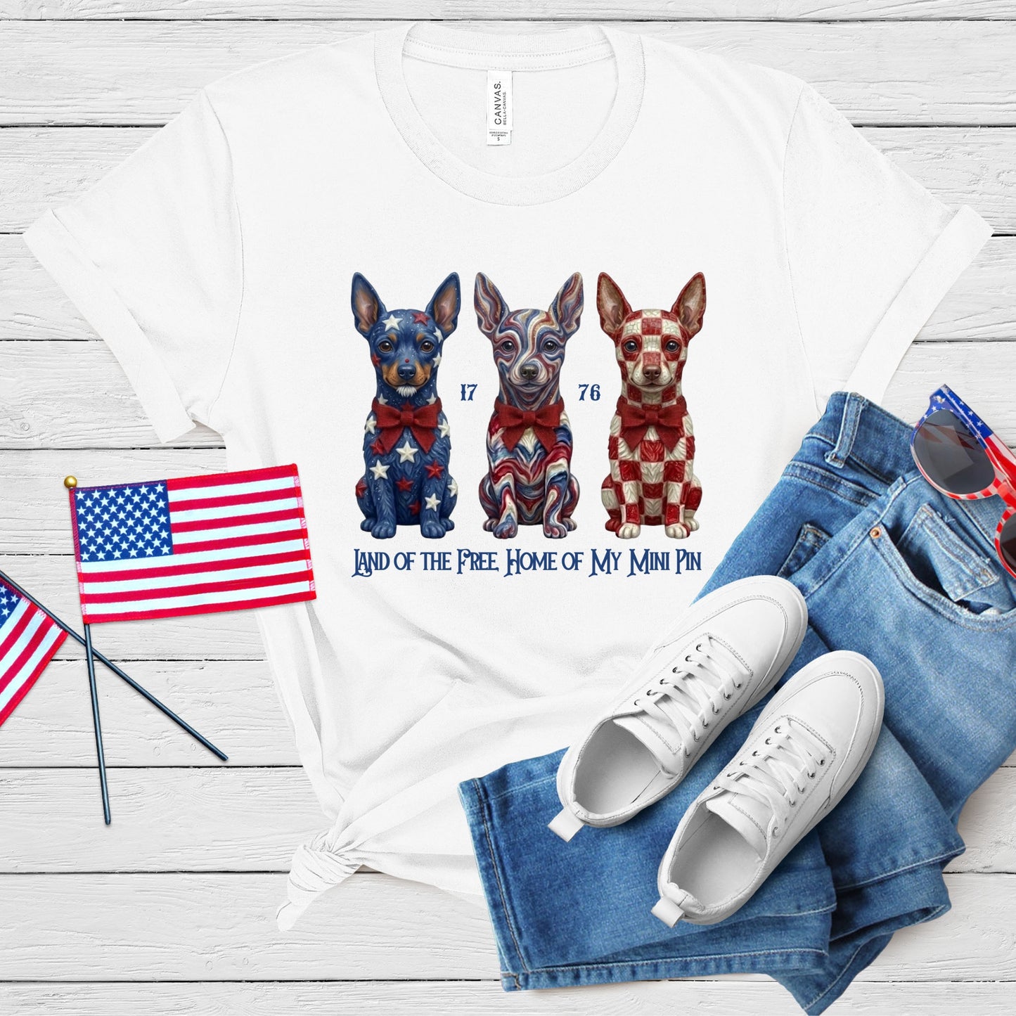 White t-shirt with dog illustration, American flags, and jeans on a wooden surface