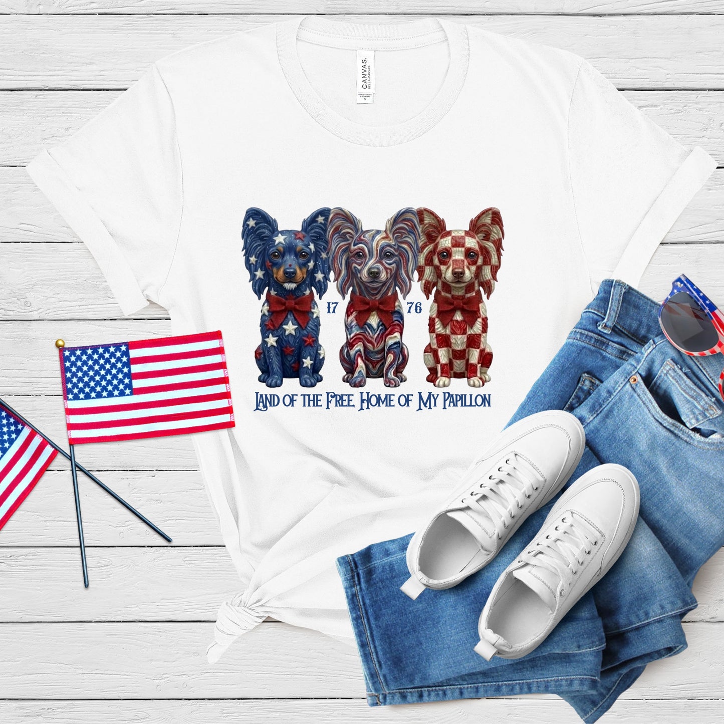White t-shirt with dog illustration, American flags, and jeans on a wooden surface