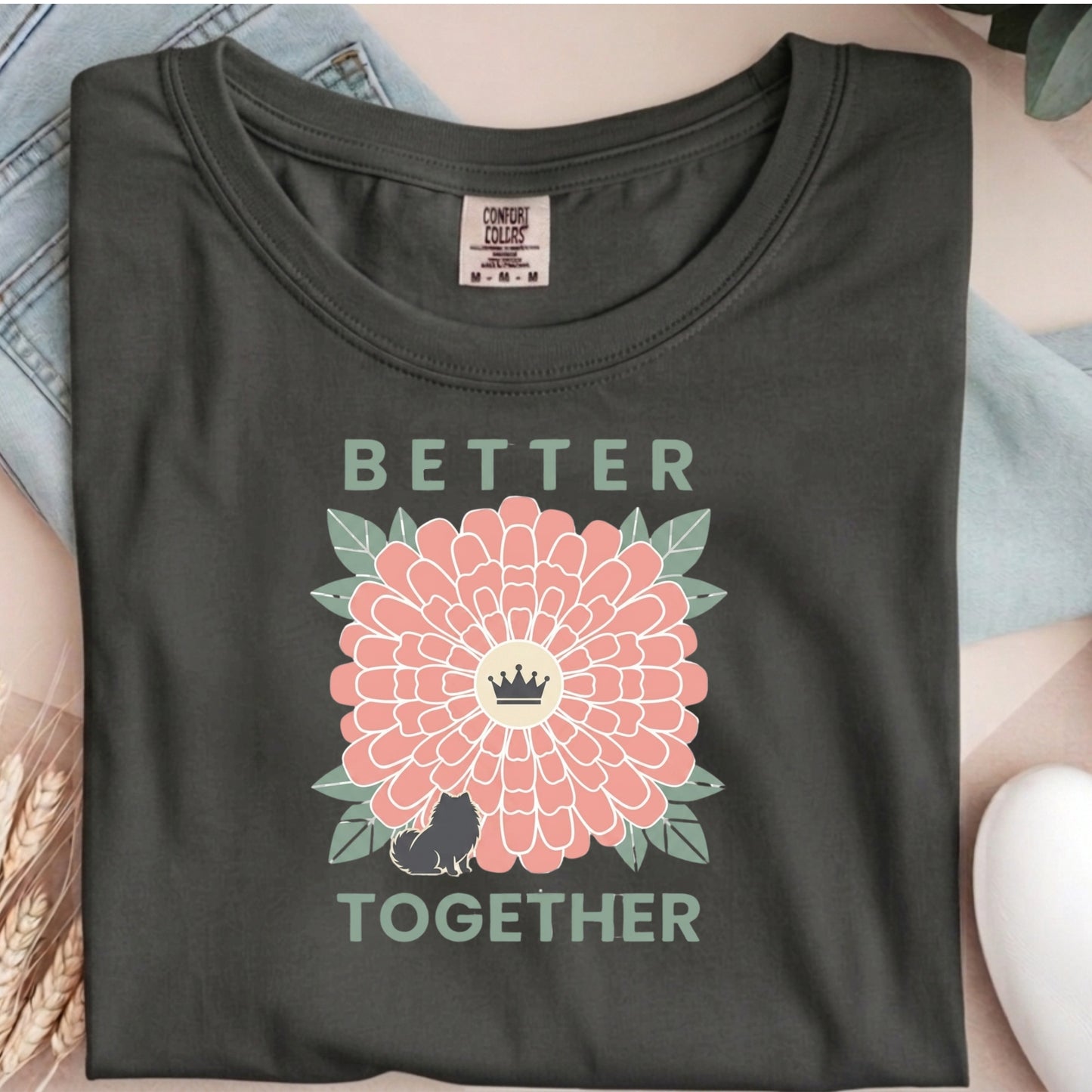 Dark gray t-shirt with a pink flower and text graphic on a neutral background