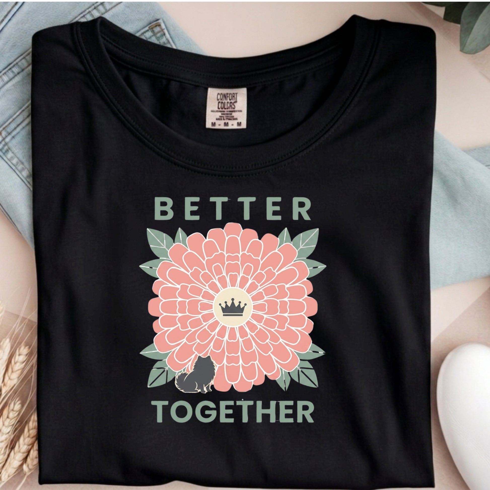 Black t-shirt with a pink flower and text design on a neutral background
