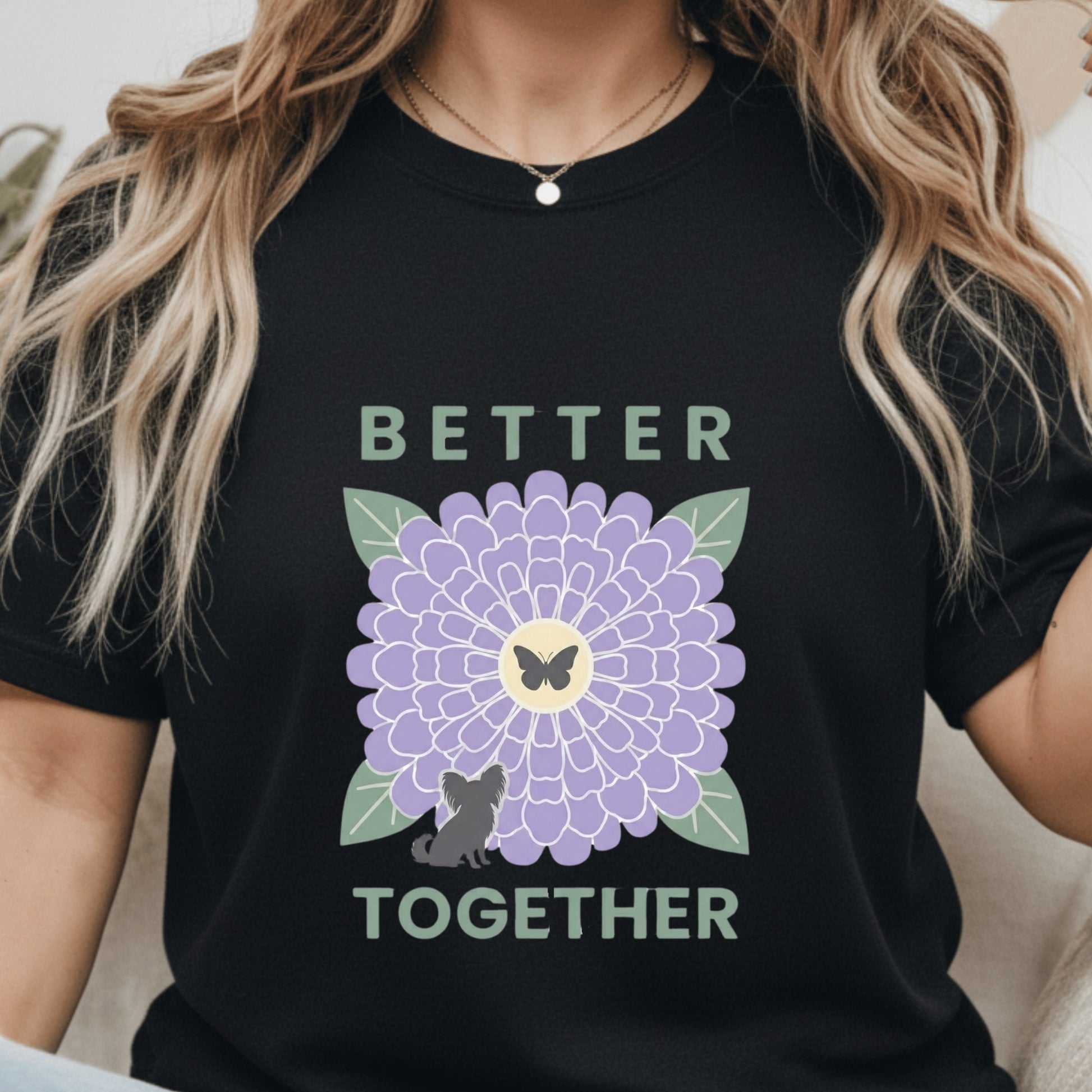 Person wearing a black t-shirt with a purple flower and text design.