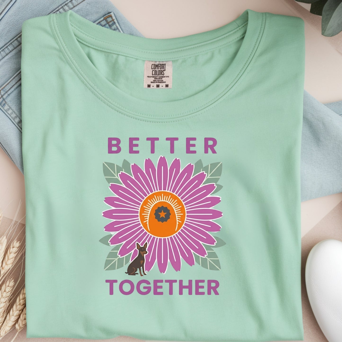 Light green t-shirt with a purple flower graphic and 'Better Together' text on a neutral background