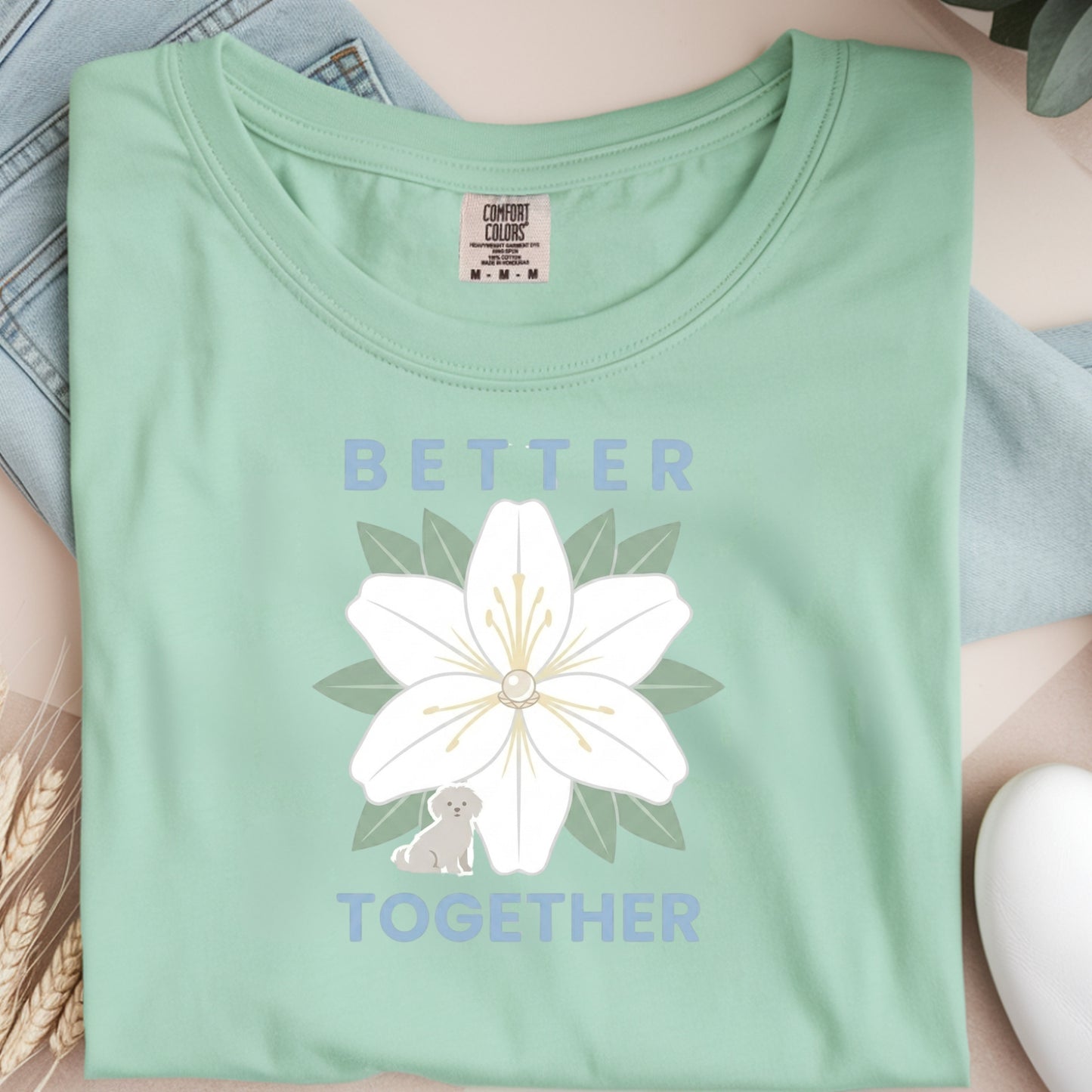 Light green t-shirt with a white flower graphic and 'Better Together' text on a neutral background