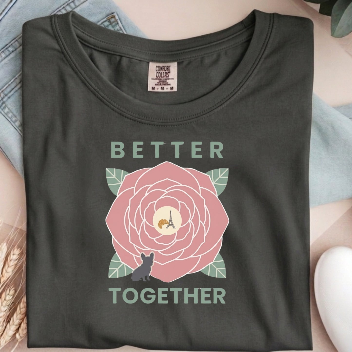 Dark gray t-shirt with a pink flower and text graphic on a light blue fabric background