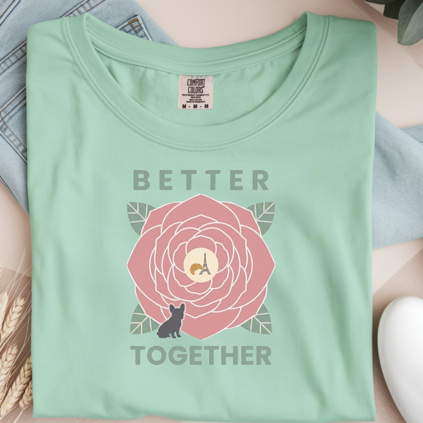 Light green t-shirt with a pink flower graphic and 'Better Together' text on a neutral background