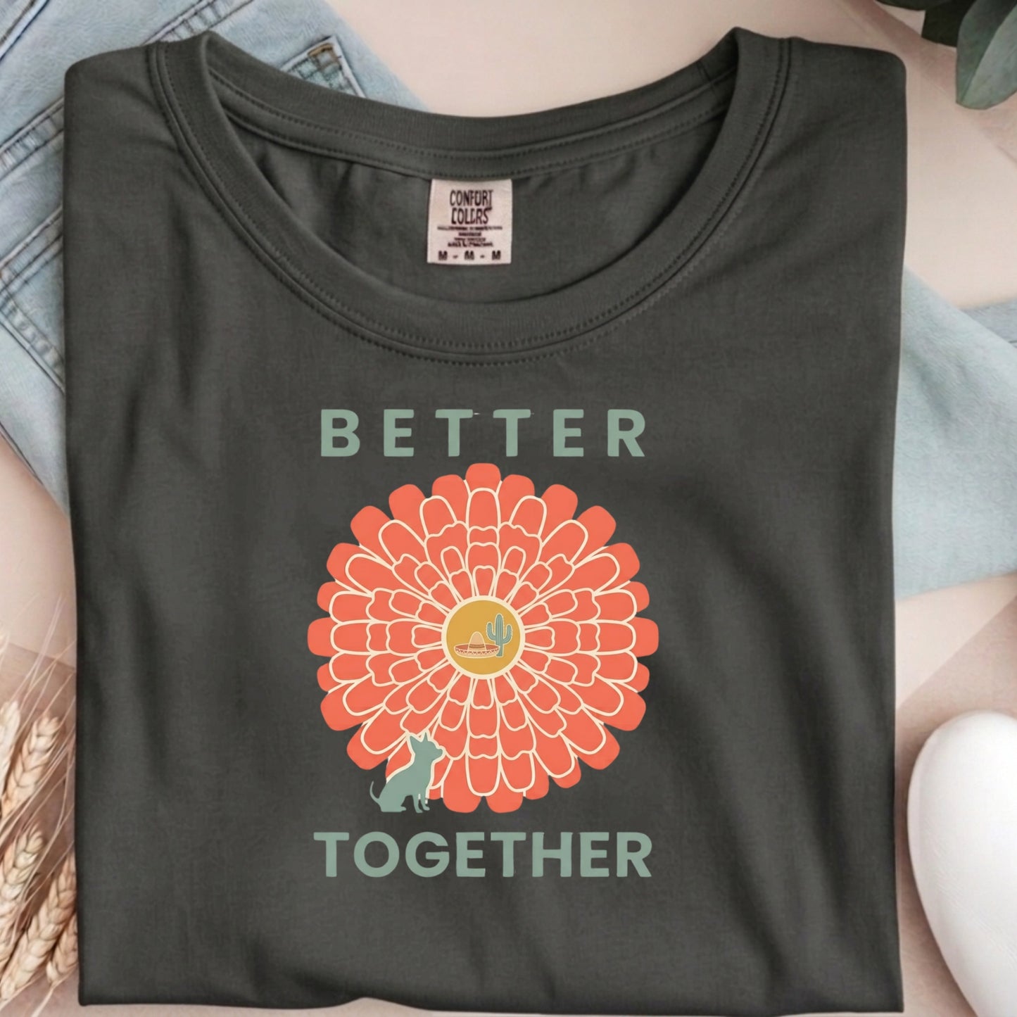 Dark gray t-shirt with a sunflower graphic and 'Better Together' text on a light blue fabric background.