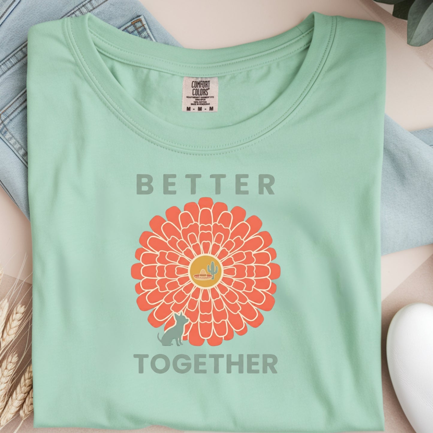 Light green t-shirt with a red floral design and 'Better Together' text on a neutral background