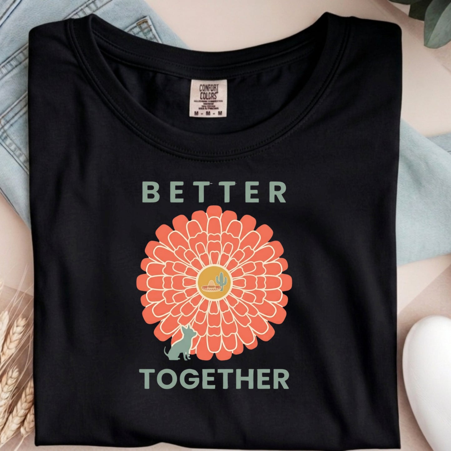 Black t-shirt with a sunflower graphic and 'Better Together' text on a light blue fabric background.