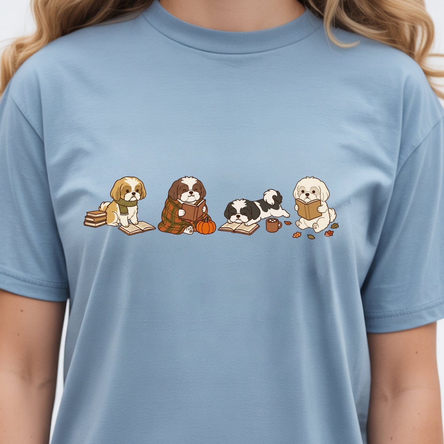 A person wearing a light blue crewneck t-shirt with a graphic print of four cute cartoon dogs reading books.