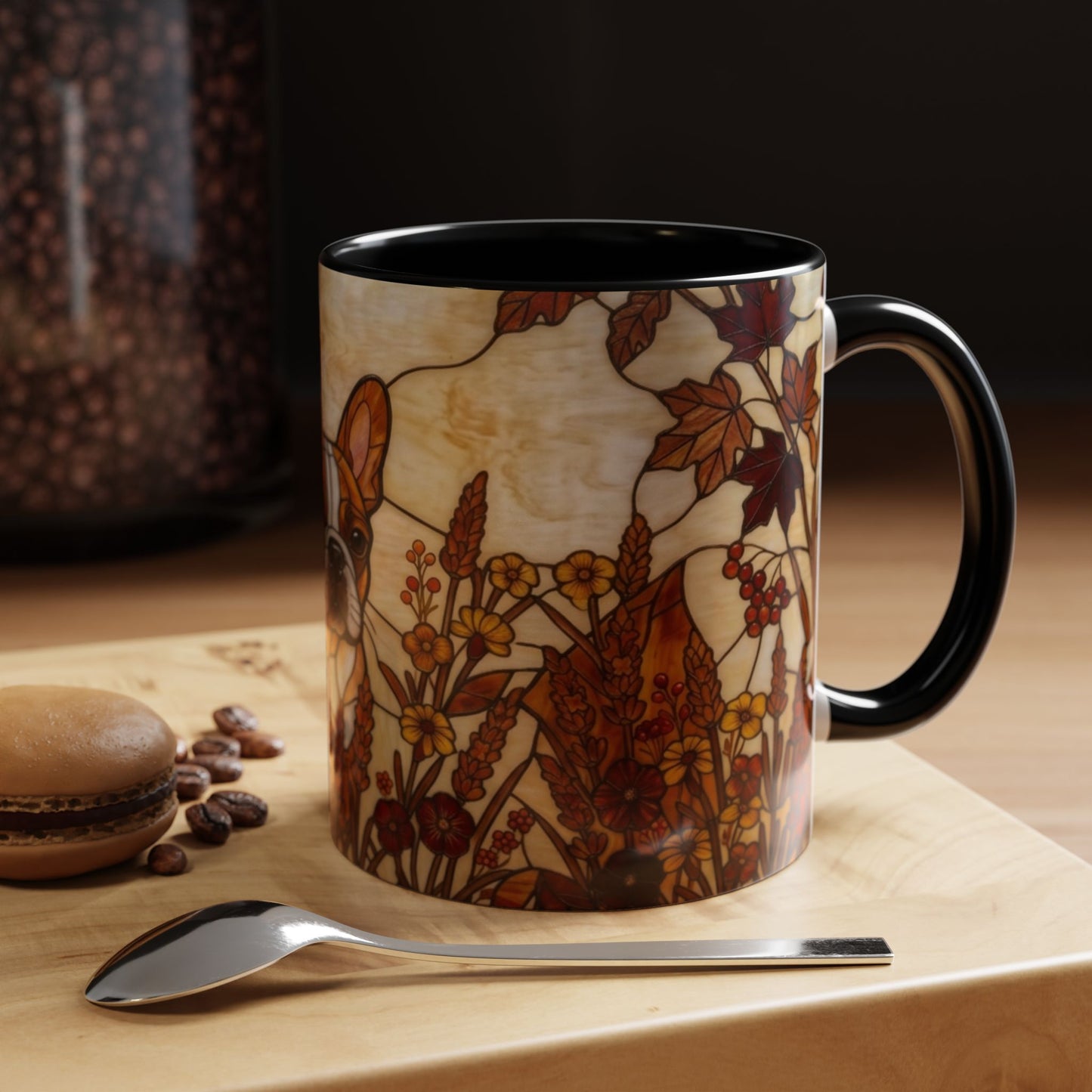 Decorative mug with autumn leaf design on a wooden surface with coffee beans and a spoon.