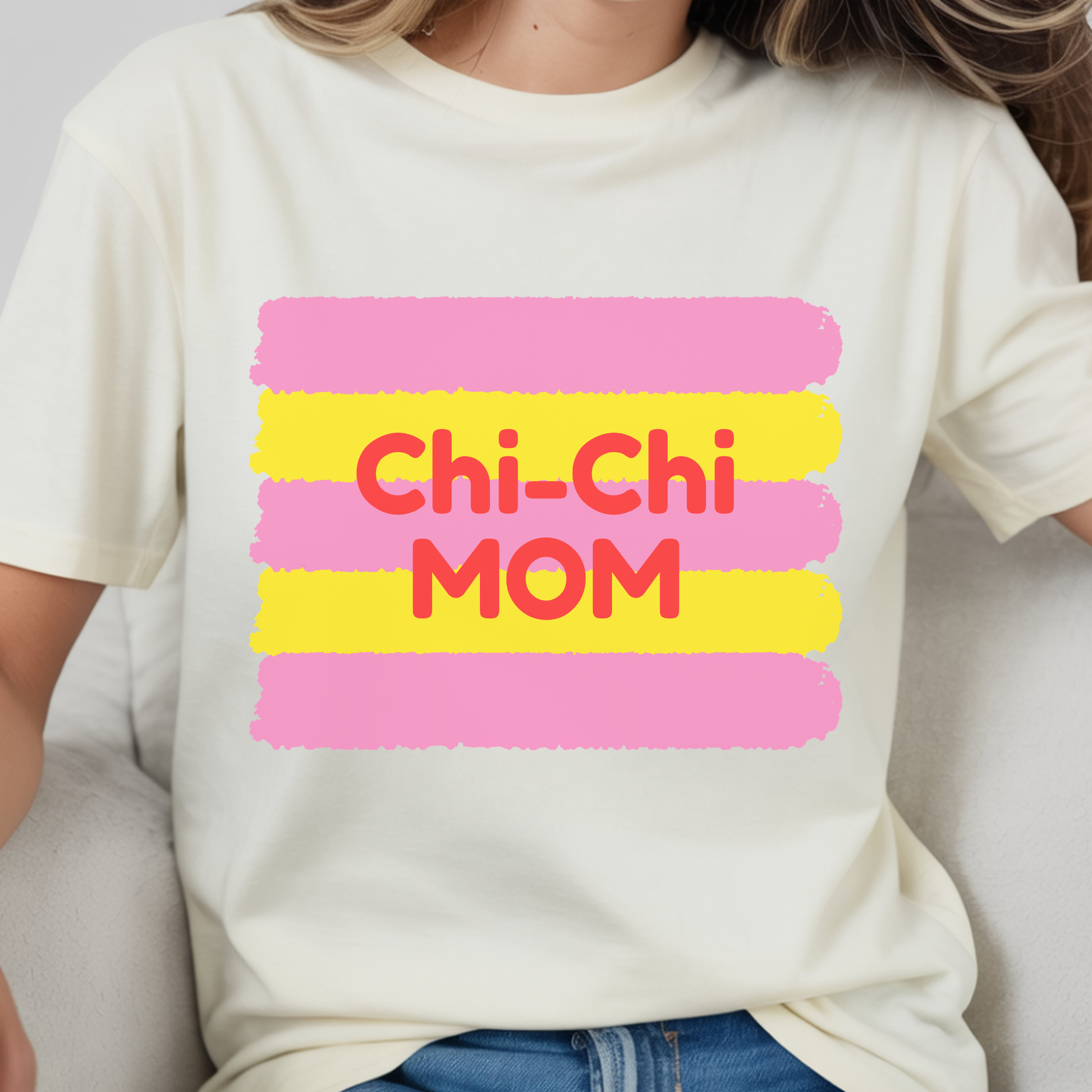 White t-shirt with 'Chi-Chi Mom' text in pink and yellow on a plain background