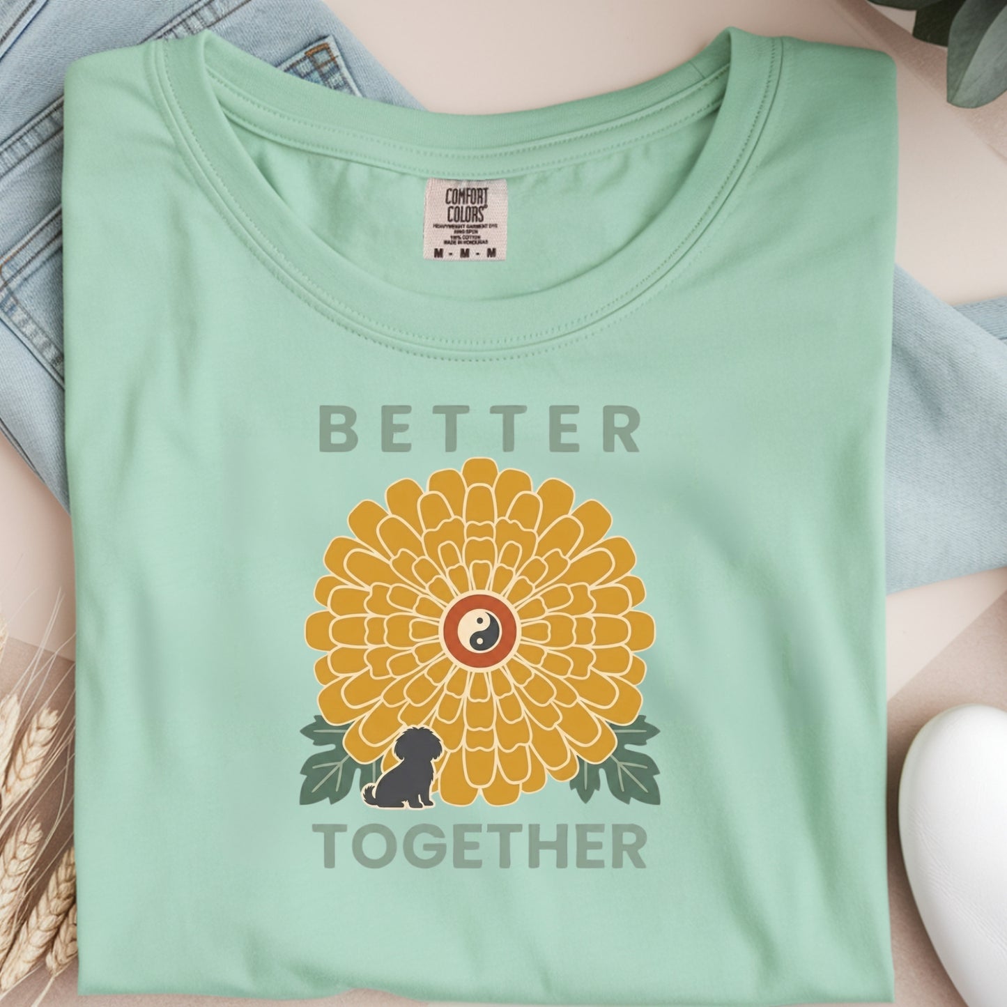 Light green t-shirt with a yellow flower design and text 'Better Together' on a neutral background.