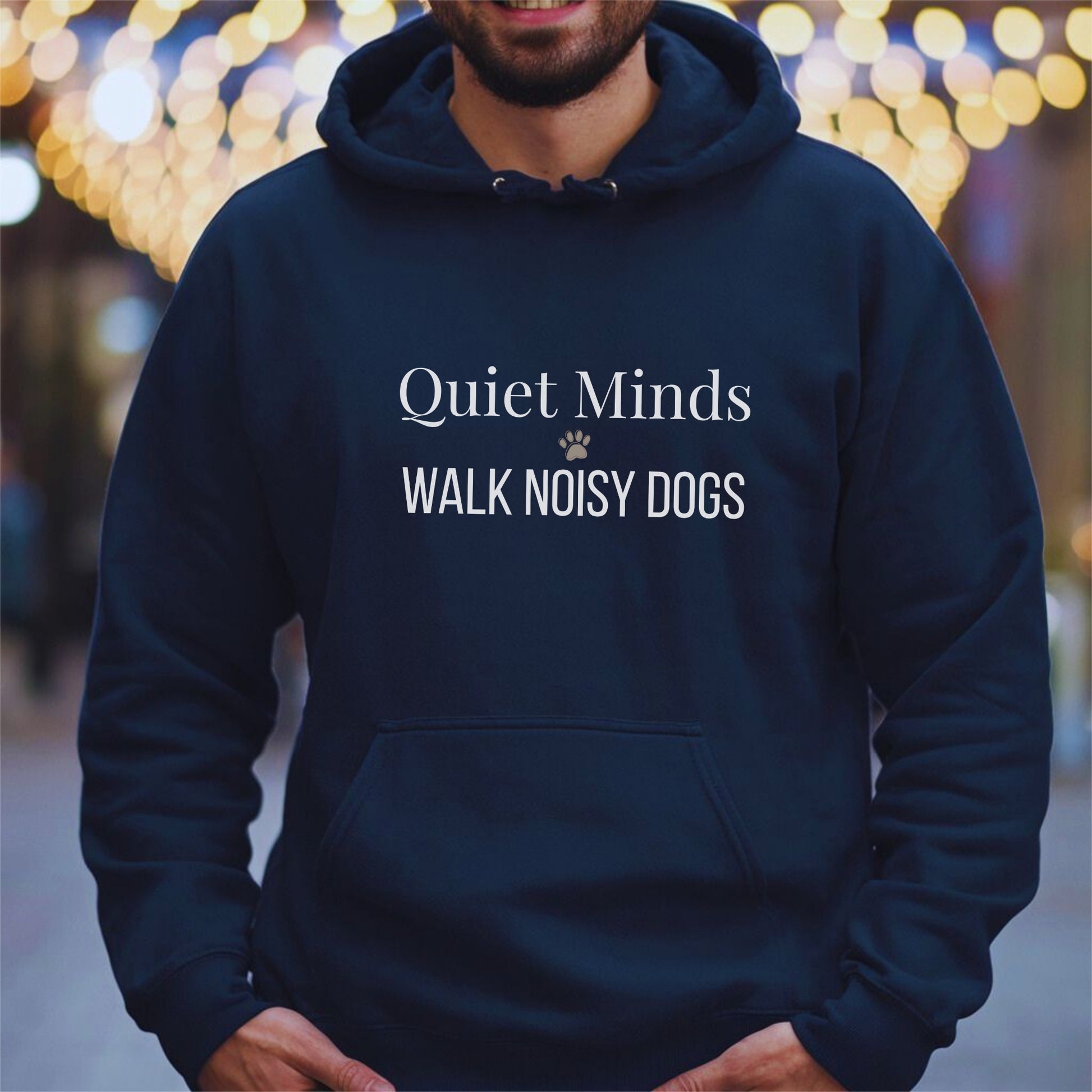Person wearing a navy hoodie with text 'Quiet Minds Walk Noisy Dogs' against a blurred bokeh background.