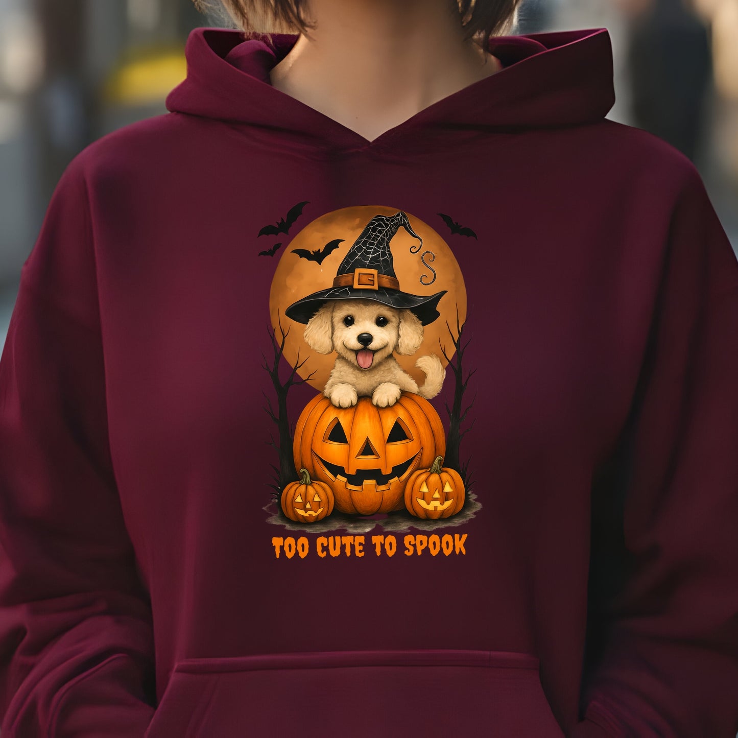 Maroon hoodie with a Halloween-themed design featuring a dog in a witch hat on a pumpkin.