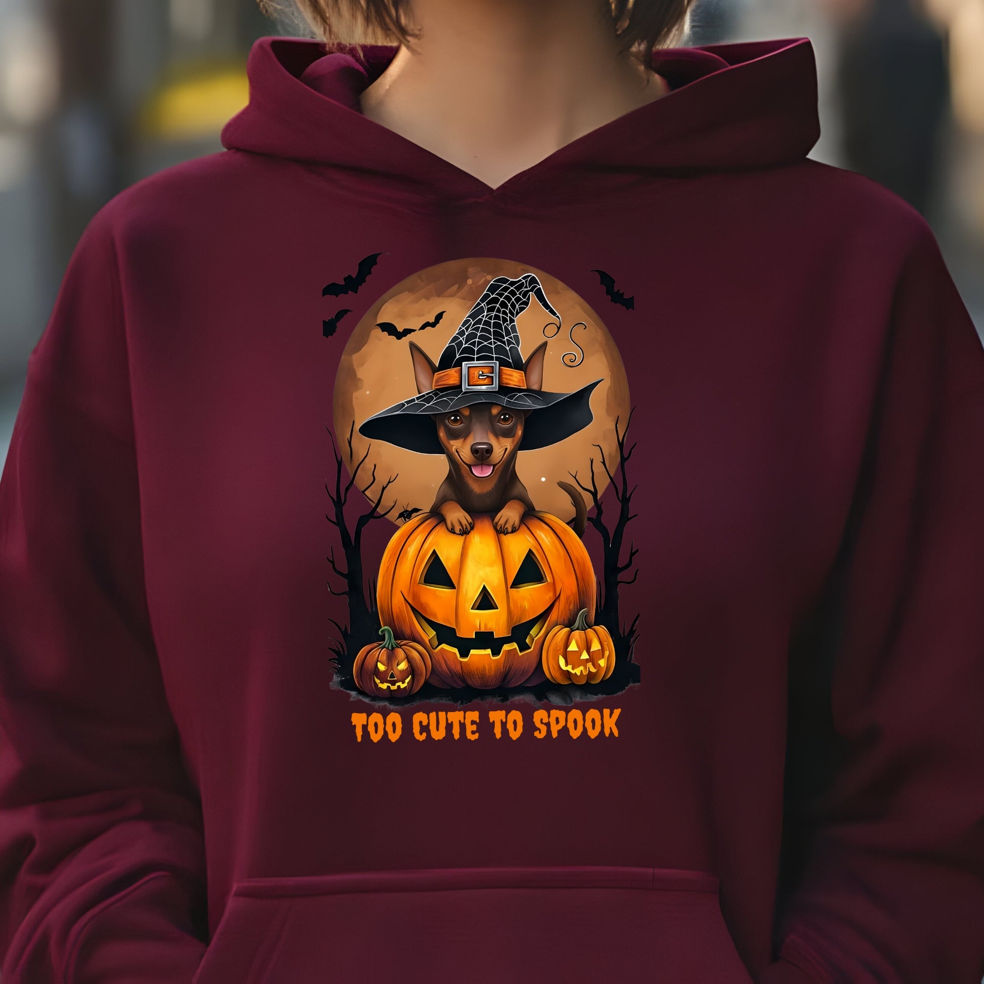 Maroon hoodie with a Halloween-themed design featuring a dog in a witch hat on a pumpkin.